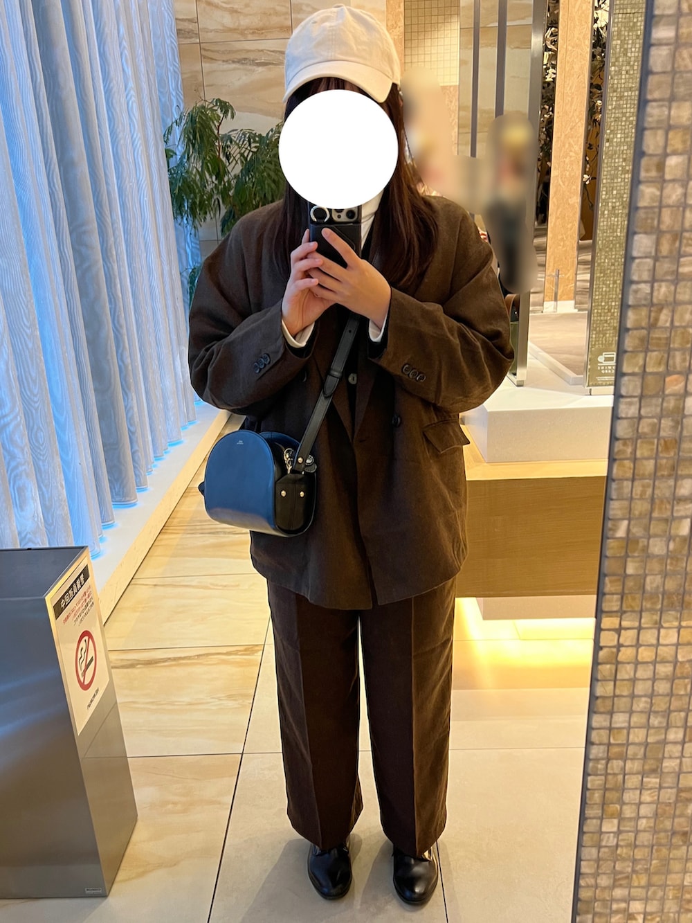 ブラック系のショルダーバッグ、ブラウン系のセットアップ、ブラック系のレインシューズを着用したレディースの冬コーディネートの2枚目の写真