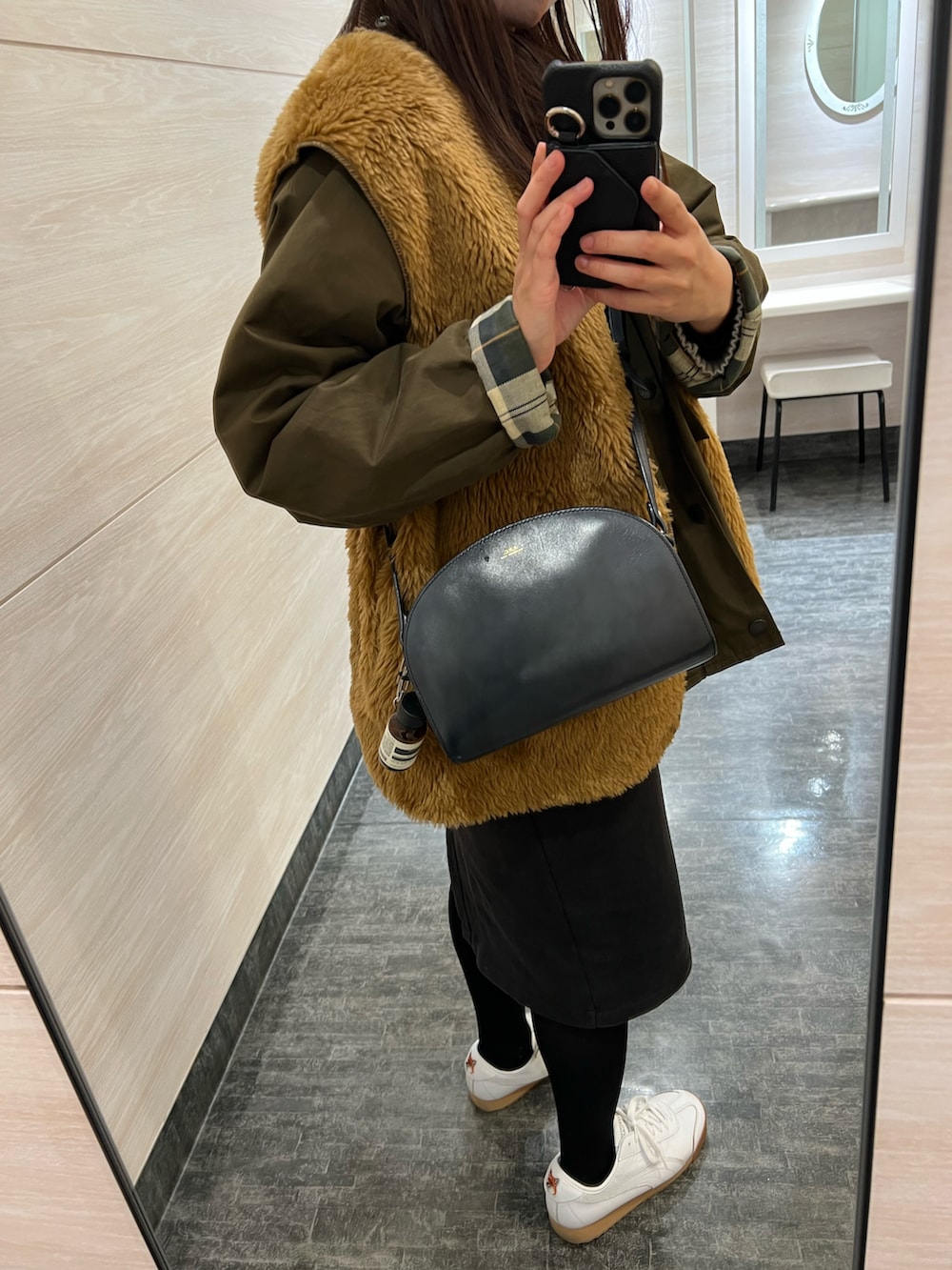 ブラウン系のベスト、グリーン系のブルゾン、ブラック系のショルダーバッグを着用したレディースの冬コーディネートの2枚目の写真