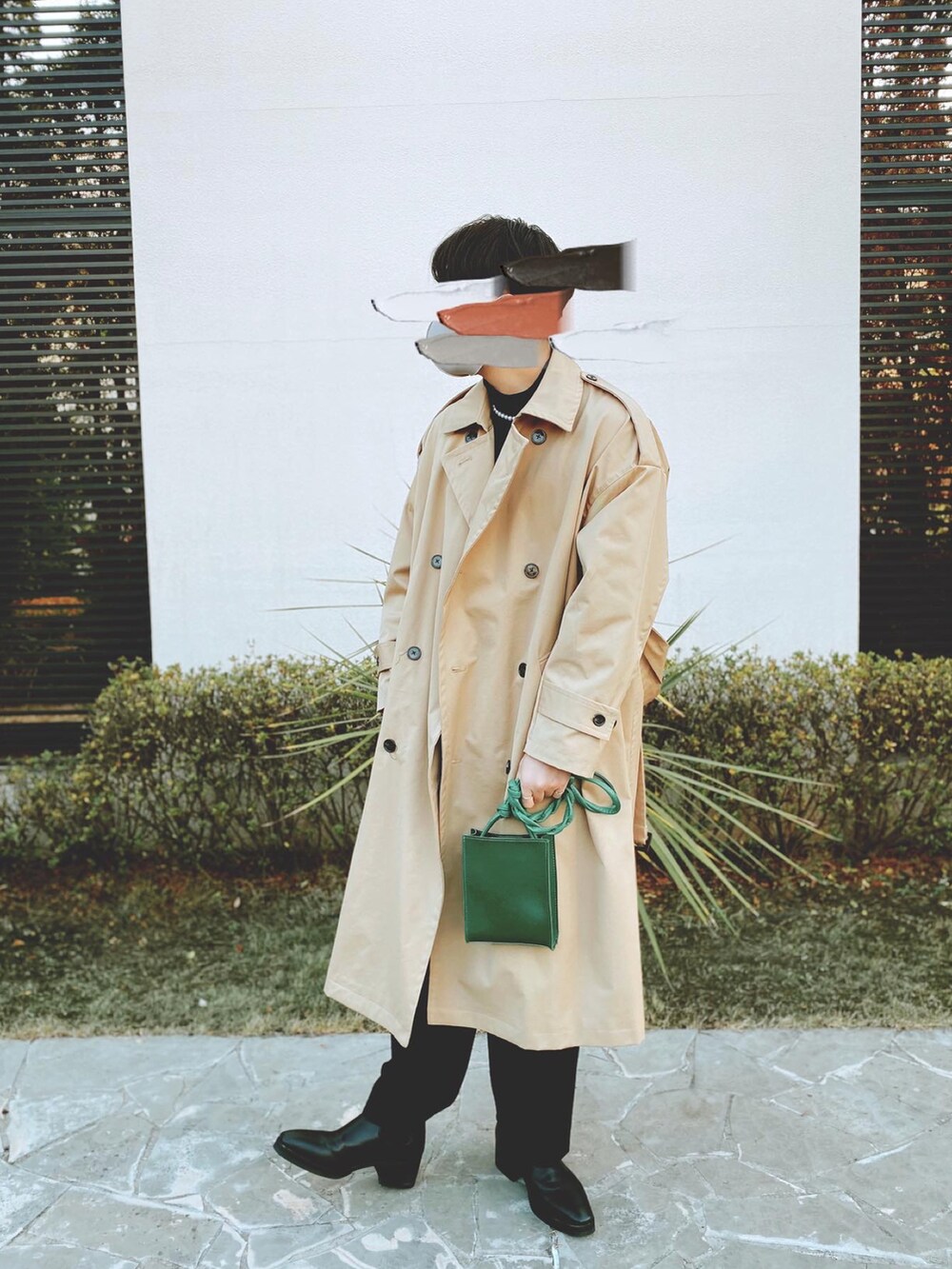 ベージュ系のトレンチコート、グリーン系のショルダーバッグ、ブラック系のスラックスを着用したメンズの冬コーディネートの2枚目の写真