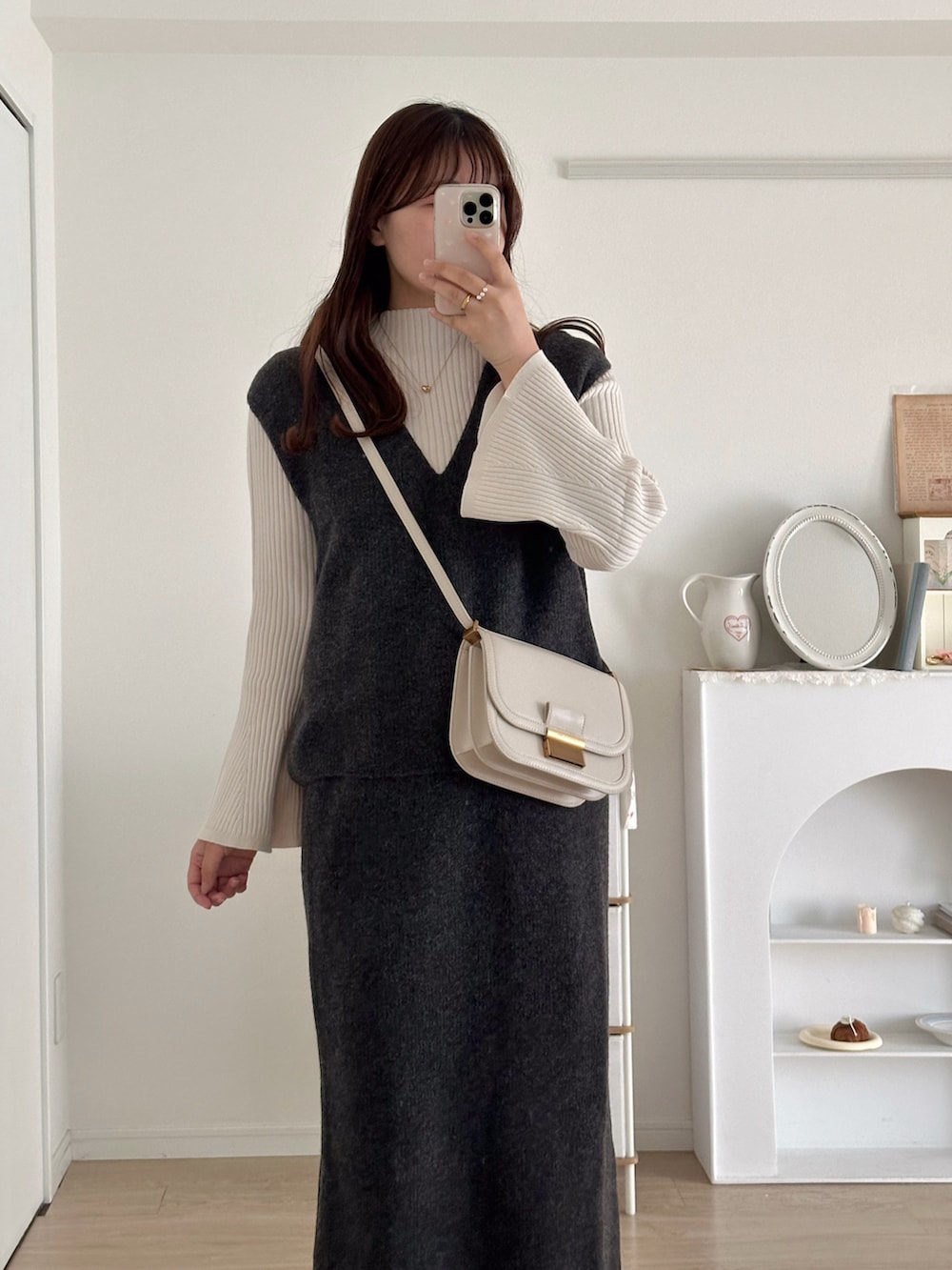 グレー系のスカート、グレー系のベスト、ホワイト系のニット/セーターを着用したレディースの秋コーディネートの2枚目の写真