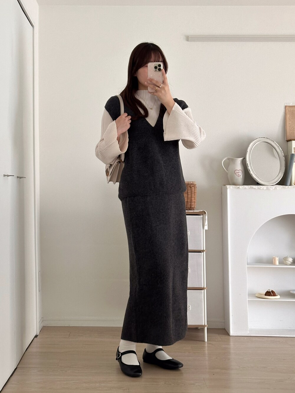 グレー系のスカート、グレー系のベスト、ホワイト系のニット/セーターを着用したレディースの秋コーディネートの4枚目の写真