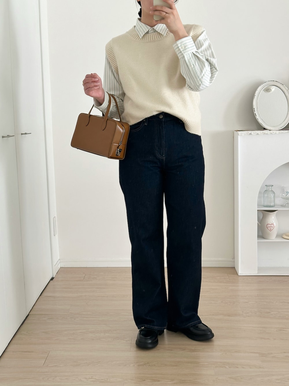 ブルー系のデニムパンツ、ホワイト系のベスト、ホワイト系のシャツ/ブラウスを着用したレディースの冬コーディネートの3枚目の写真