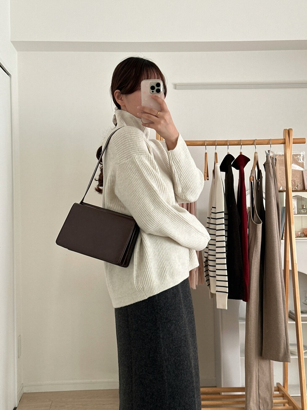 ホワイト系のニット/セーター、グレー系のスカート、ブラック系のブーツを着用したレディースの冬コーディネートの3枚目の写真