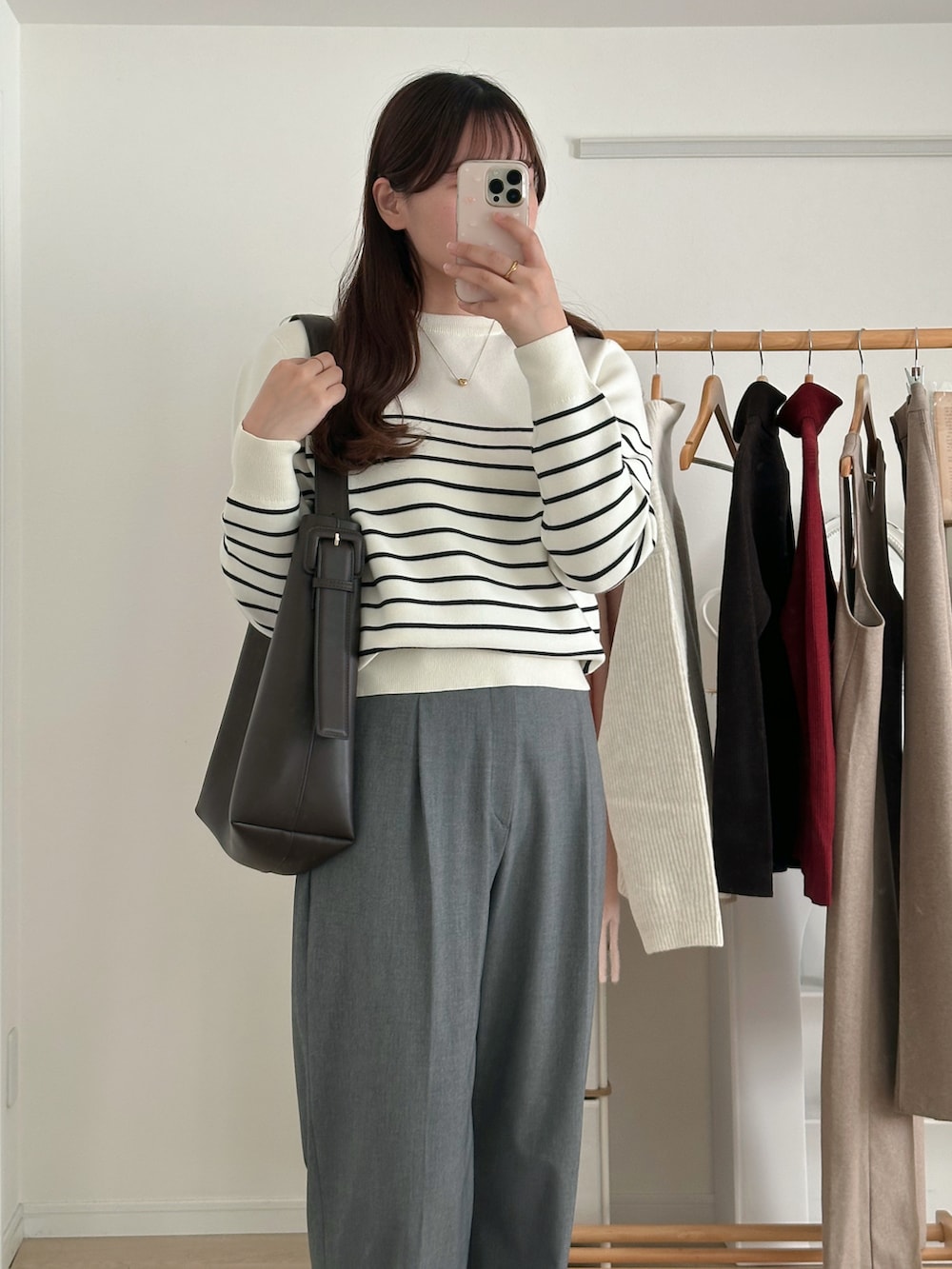 ホワイト系のニット/セーター、グレー系のパンツ、ブラウン系のバッグを着用したレディースの冬コーディネートの2枚目の写真