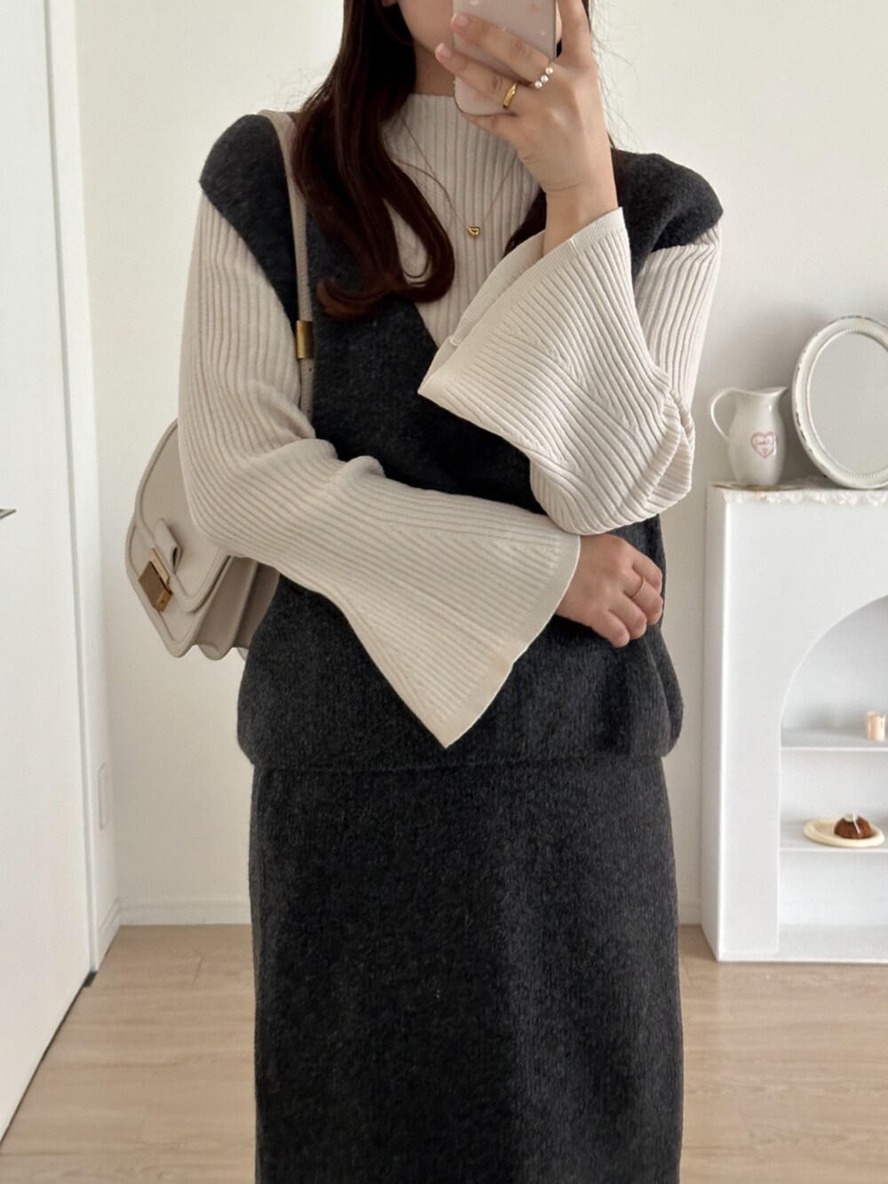 グレー系のスカート、グレー系のベスト、ホワイト系のニット/セーターを着用したレディースの秋コーディネートの5枚目の写真