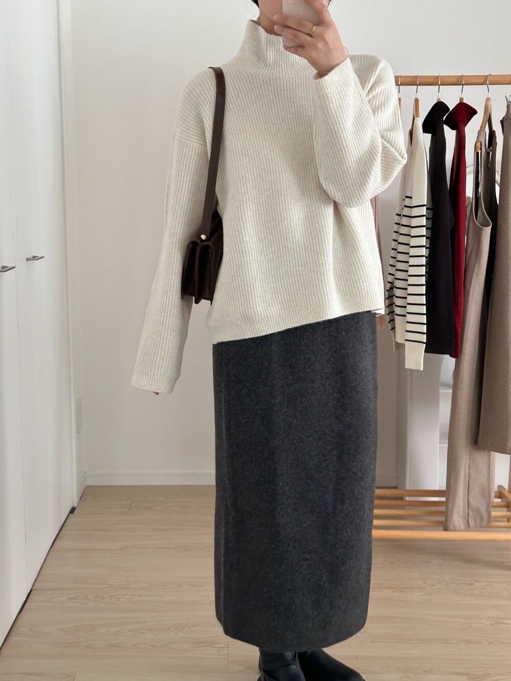 ホワイト系のニット/セーター、グレー系のスカート、ブラック系のブーツを着用したレディースの冬コーディネートの4枚目の写真