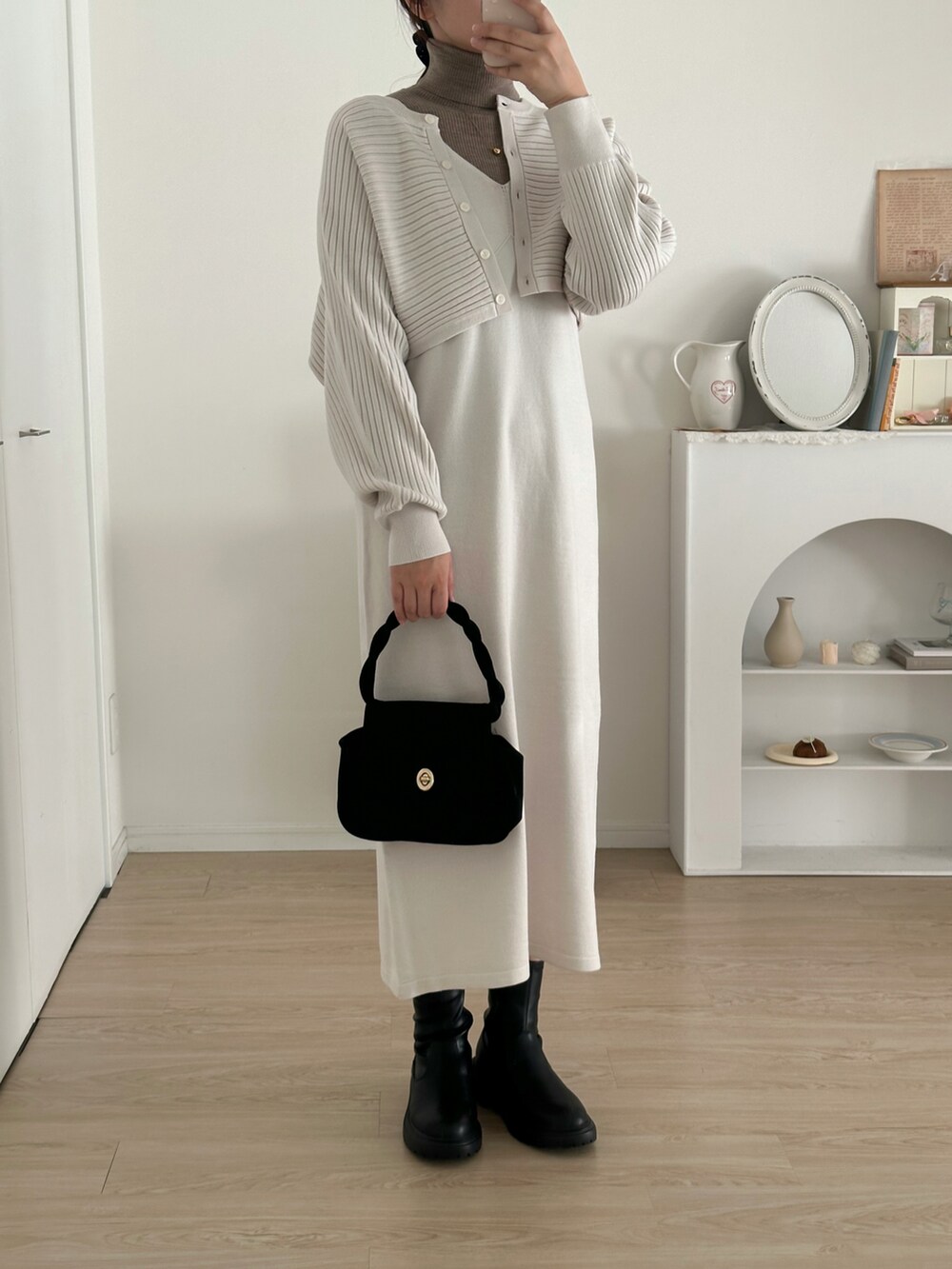 ブラック系のブーツ、ホワイト系のワンピース/ドレス、ブラウン系のニット/セーターを着用したレディースの冬コーディネートの2枚目の写真