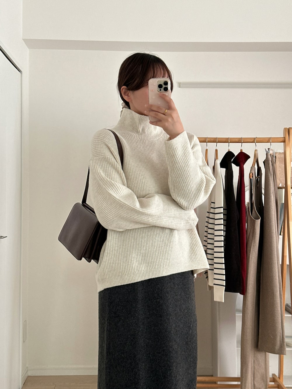 ホワイト系のニット/セーター、グレー系のスカート、ブラック系のブーツを着用したレディースの冬コーディネートの2枚目の写真