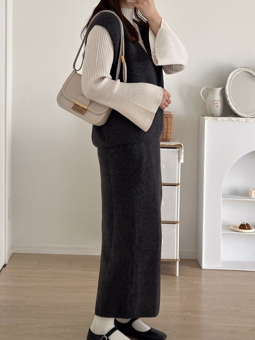 グレー系のスカート、グレー系のベスト、ホワイト系のニット/セーターを着用したレディースの秋コーディネートの3枚目の写真