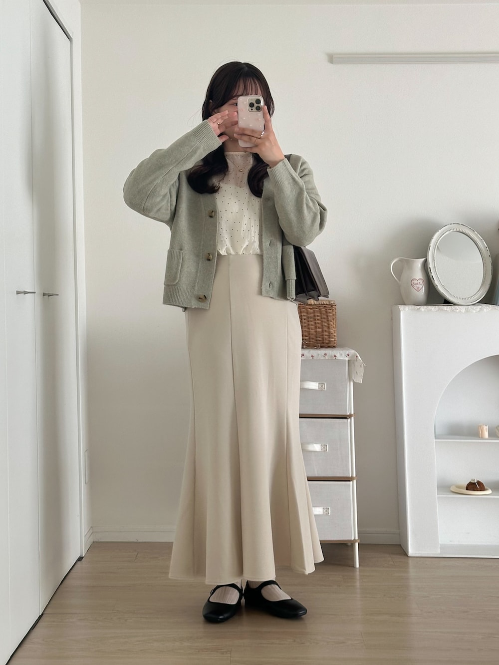 ブラック系のシューズ、ホワイト系のスカート、グリーン系のニット/セーターを着用したレディースの秋コーディネートの2枚目の写真