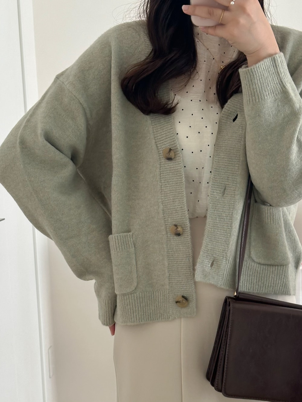 ブラック系のシューズ、ホワイト系のスカート、グリーン系のニット/セーターを着用したレディースの秋コーディネートの3枚目の写真