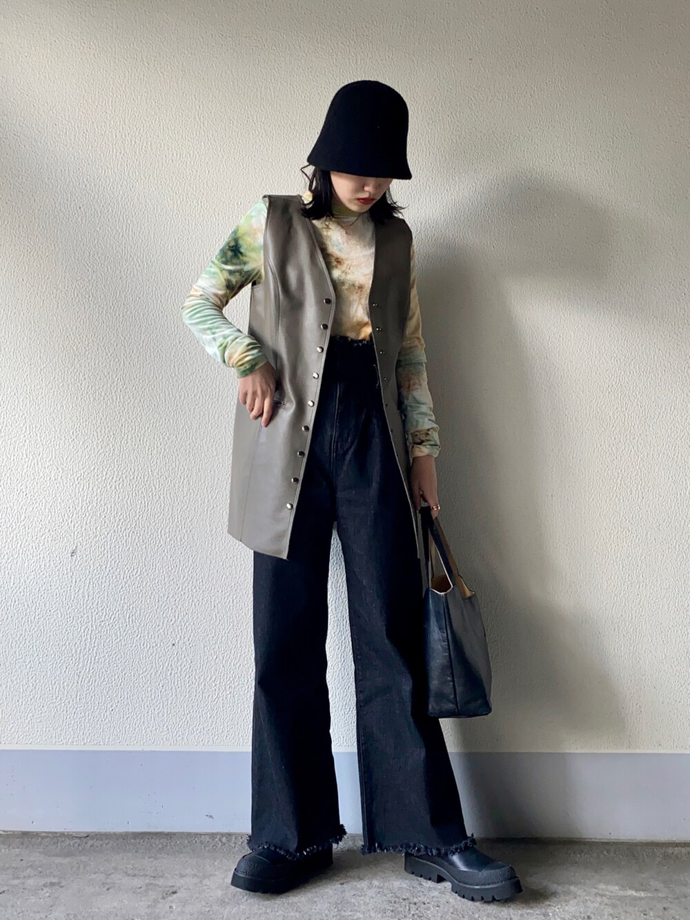 グリーン系のベスト、グリーン系のTシャツ/カットソー、ブラック系のハンドバッグを着用したレディースの冬コーディネートの2枚目の写真