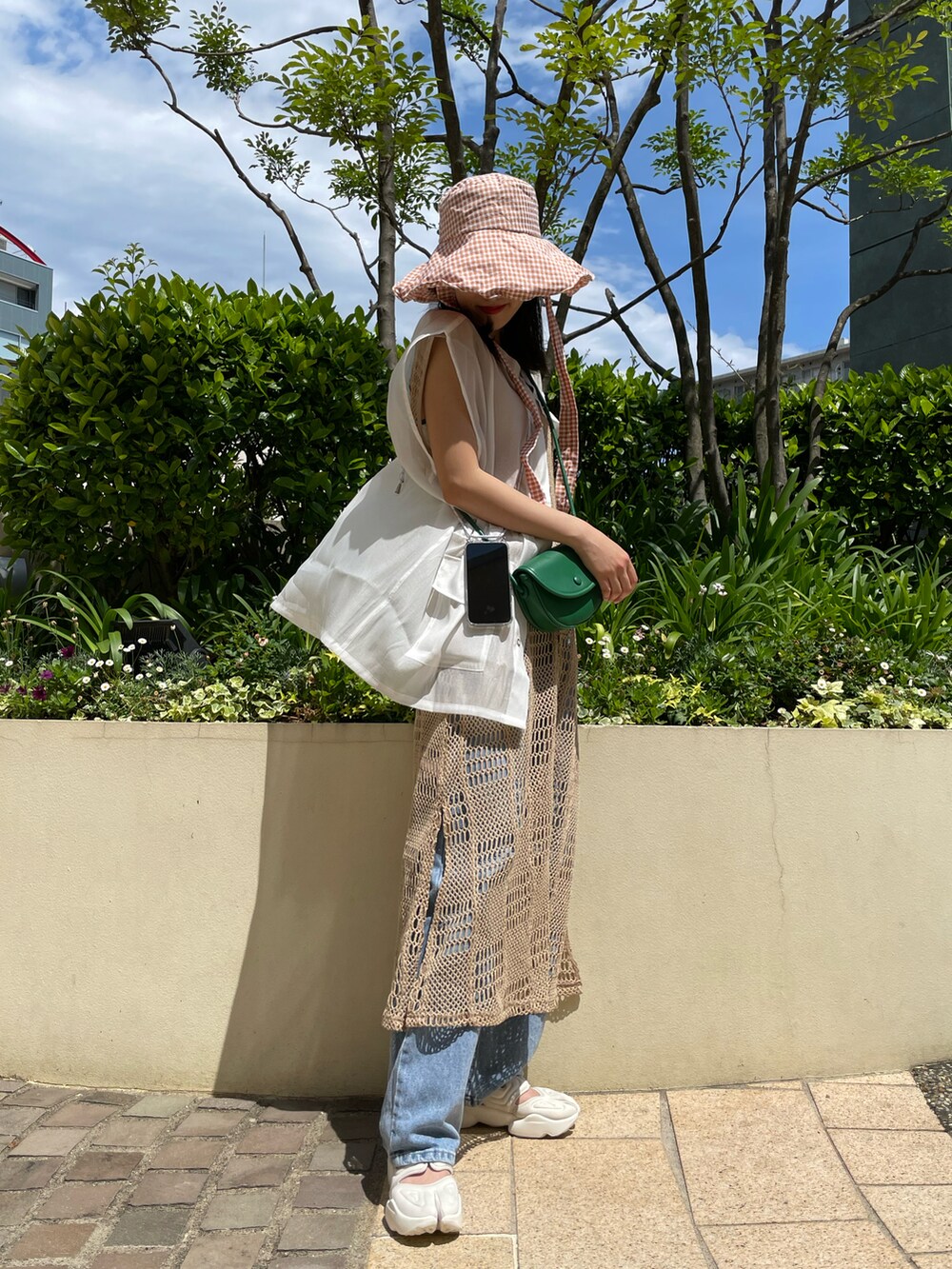 ホワイト系のベスト、ブラック系のベスト、グリーン系のショルダーバッグを着用したレディースの夏コーディネートの2枚目の写真