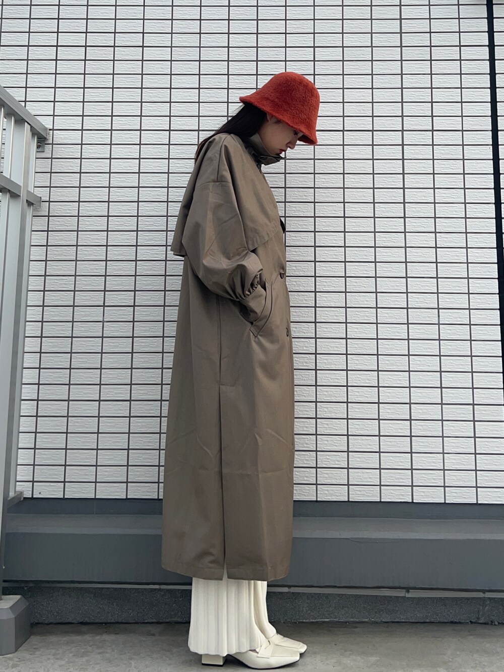 グリーン系のトレンチコート、ホワイト系のその他パンツ、ホワイト系のローファーを着用したレディースの冬コーディネートの2枚目の写真