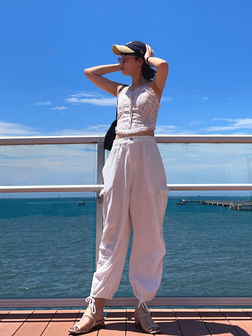 ブラック系のハンドバッグ、ホワイト系のキャミソール、ホワイト系のカーゴパンツを着用したレディースの夏コーディネートの2枚目の写真