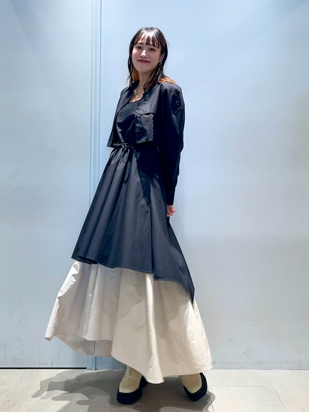 ブラック系のシャツワンピース、ベージュ系のスカート、ベージュ系のブーツを着用したレディースの秋コーディネートの2枚目の写真