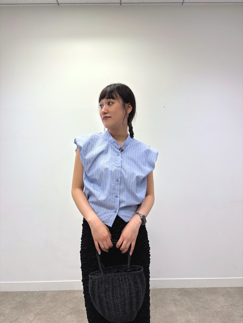 ブラック系のスカート、ブラック系のハンドバッグ、ブルー系のシャツ/ブラウスを着用したレディースの夏コーディネートの2枚目の写真