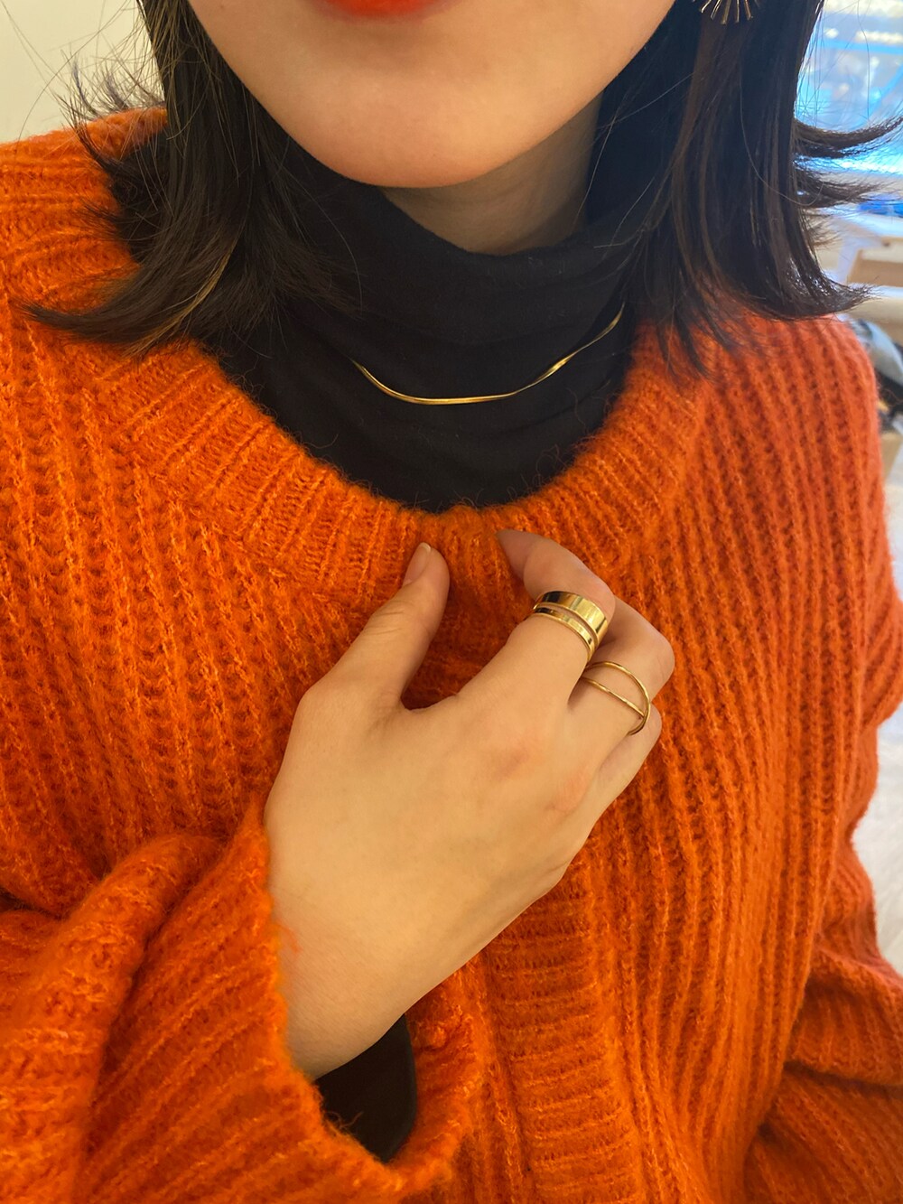 オレンジ系のカーディガン/ボレロ、ブラック系のTシャツ/カットソー、ブラウン系のボストンバッグを着用したレディースの冬コーディネートの2枚目の写真