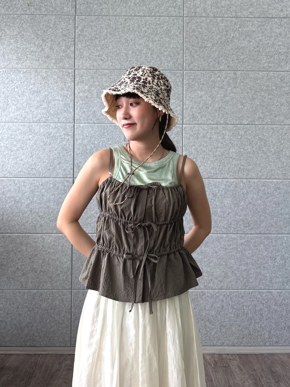 グリーン系のタンクトップ、ホワイト系のスカート、ベージュ系のハットを着用したレディースの夏コーディネートの2枚目の写真