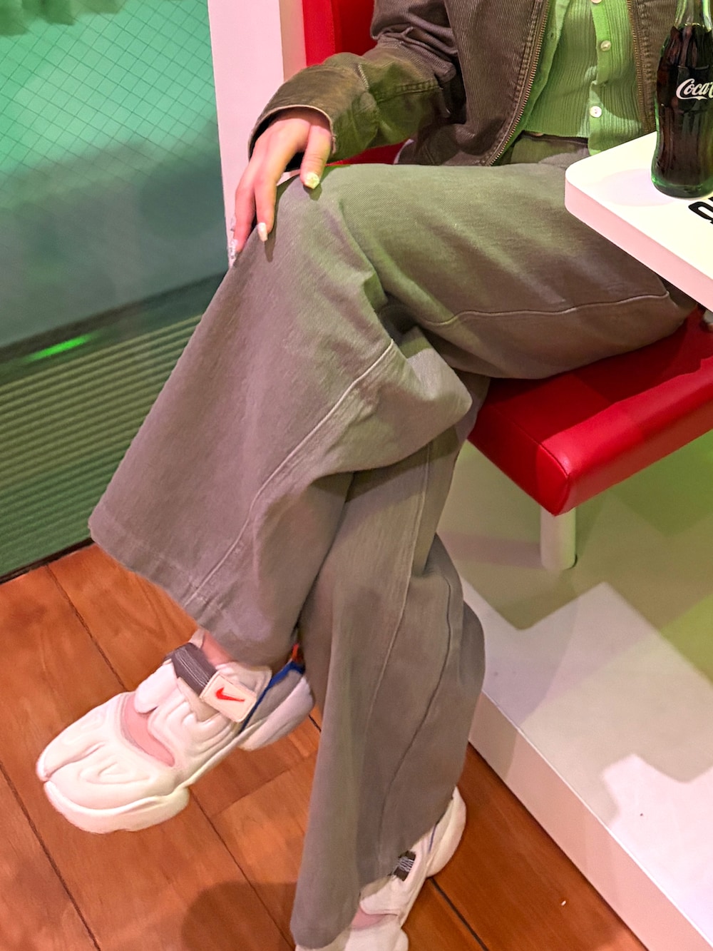 グリーン系のライダースジャケット、グレー系のデニムパンツ、ブラック系のショルダーバッグを着用したレディースの春コーディネートの2枚目の写真