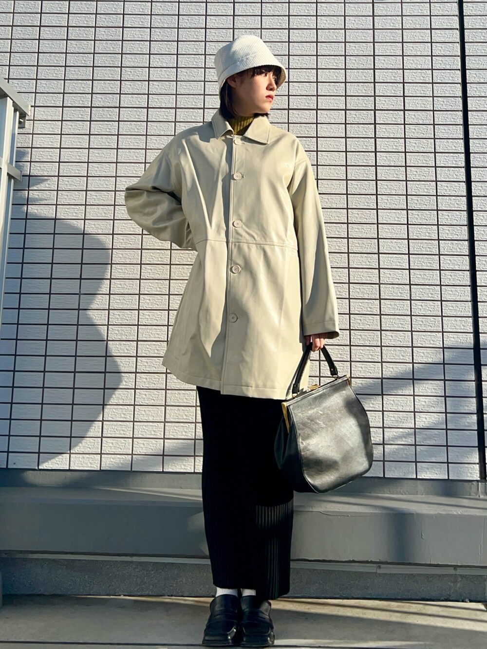 ホワイト系のその他アウター、グリーン系のニット/セーター、ブラック系のハンドバッグを着用したレディースの春コーディネートの2枚目の写真