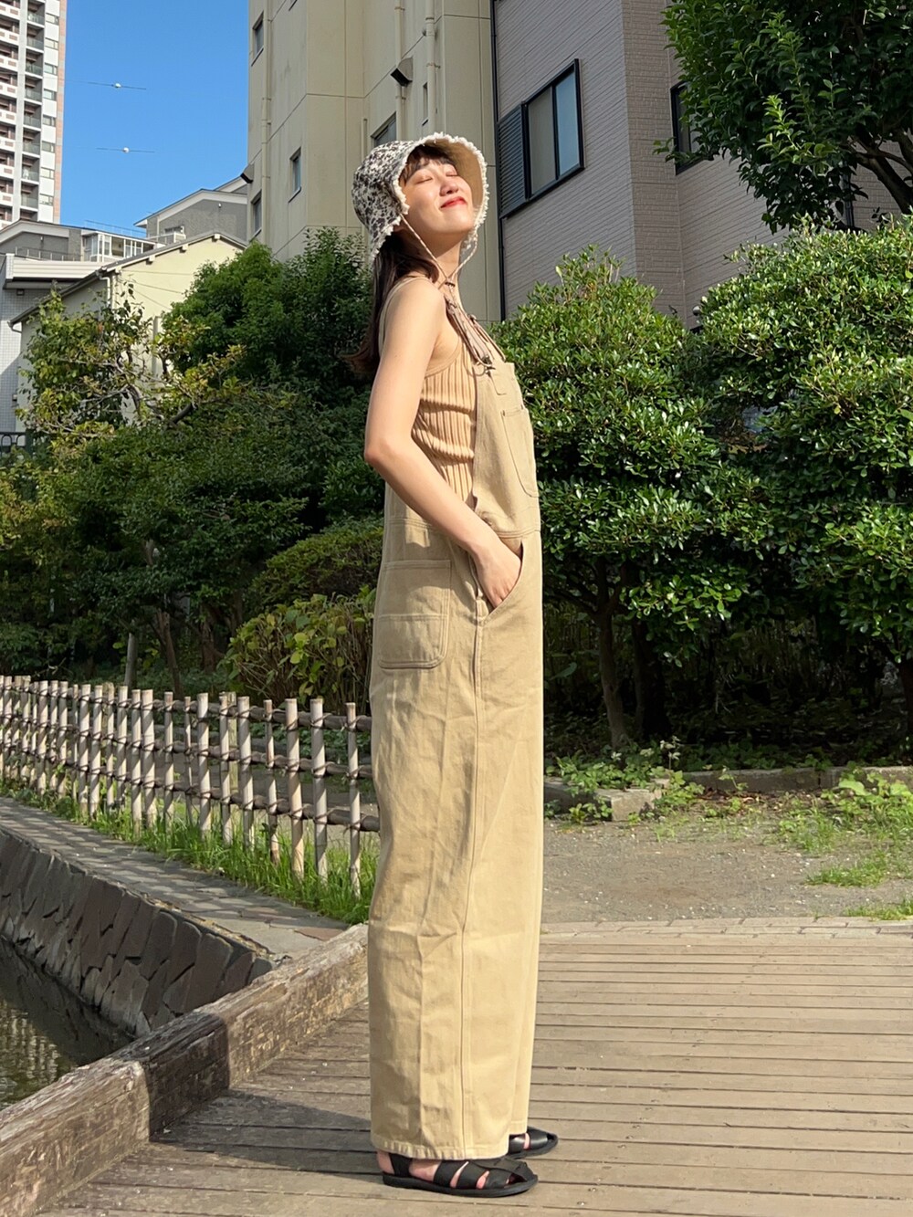 ベージュ系のキャミソール、ベージュ系のサロペット/オーバーオール、ブラック系のサンダルを着用したレディースの夏コーディネートの2枚目の写真