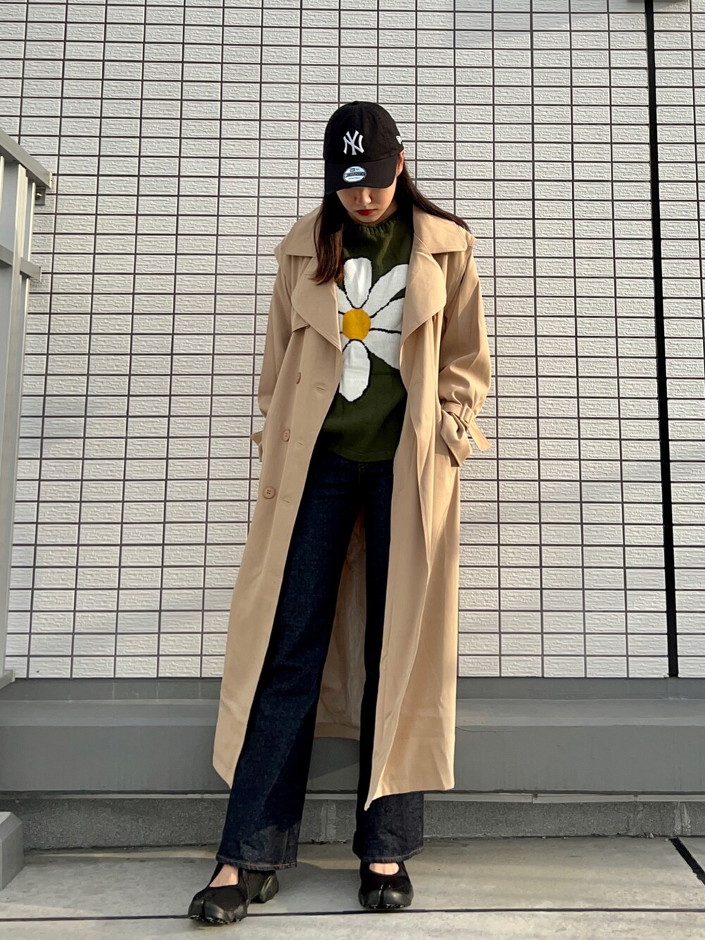 グリーン系のニット/セーター、ブルー系のデニムパンツ、ブラック系のスニーカーを着用したレディースの秋コーディネートの2枚目の写真