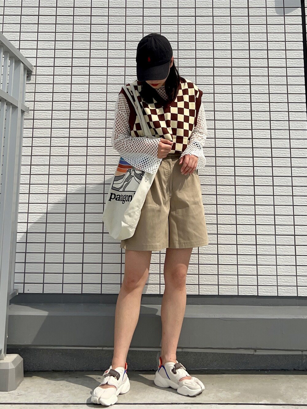 ブラウン系のベスト、その他のトートバッグ、ホワイト系のサンダルを着用したレディースの夏コーディネートの2枚目の写真