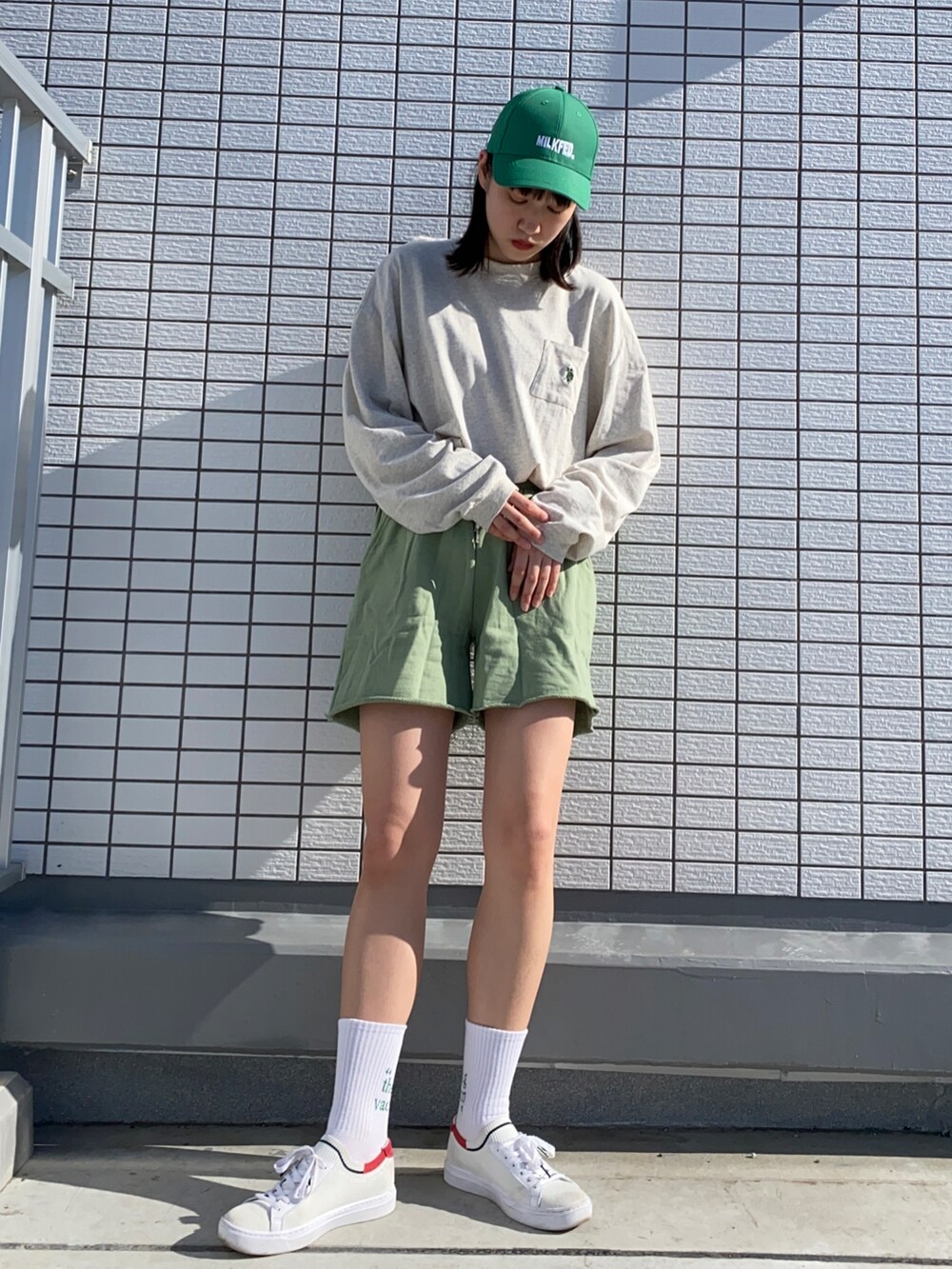 グリーン系のダウンベスト、ベージュ系のTシャツ/カットソー、グリーン系のスウェットパンツを着用したレディースの春コーディネートの2枚目の写真