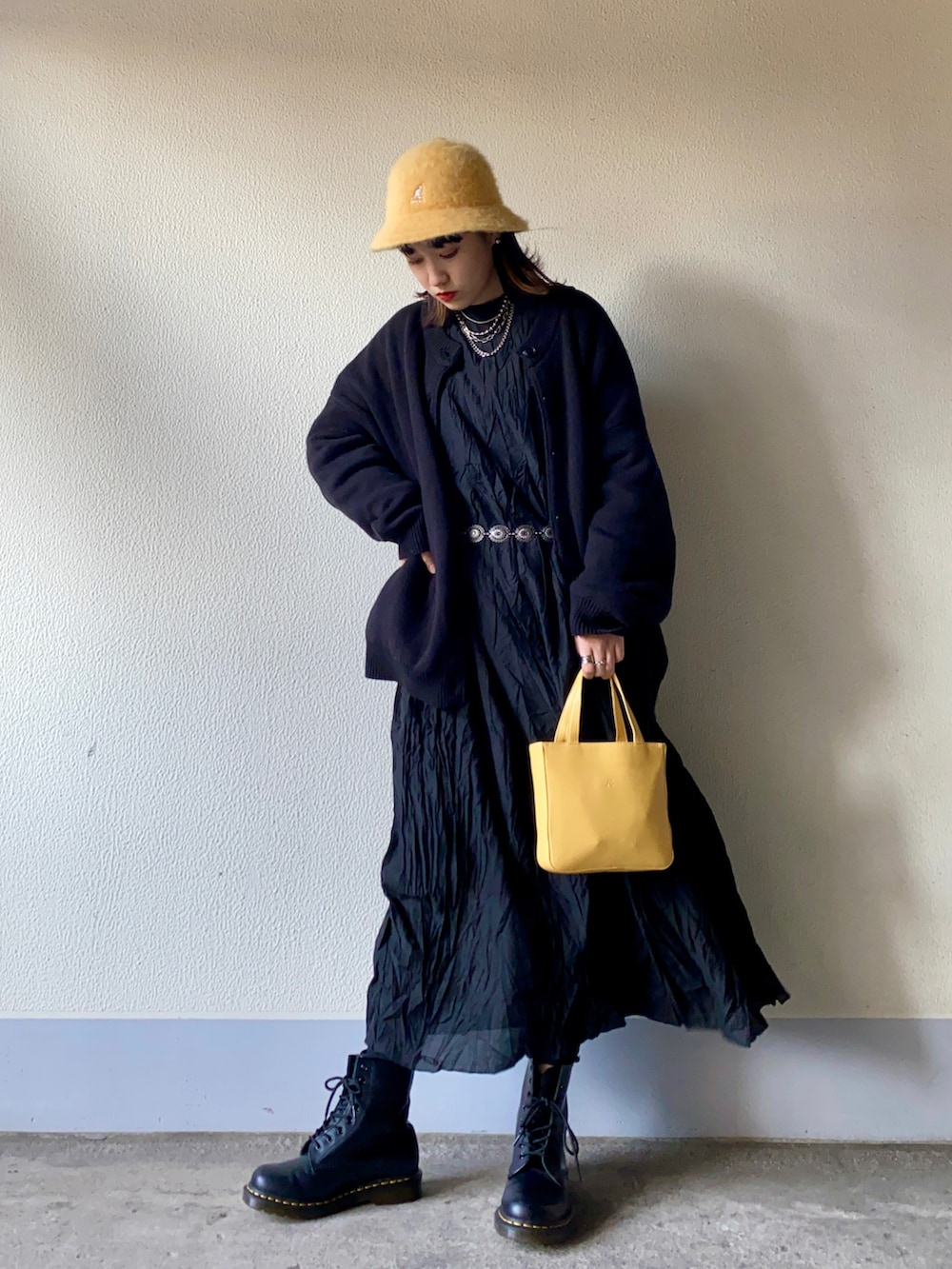 ブラック系のカーディガン/ボレロ、ブラック系のワンピース、イエロー系のハンドバッグを着用したレディースの冬コーディネートの2枚目の写真