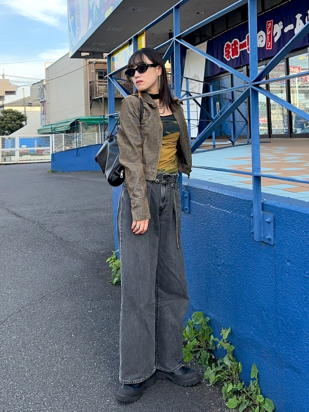 グリーン系のライダースジャケット、ブラック系のハンドバッグ、ブラック系のTシャツ/カットソーを着用したレディースの秋コーディネートの2枚目の写真