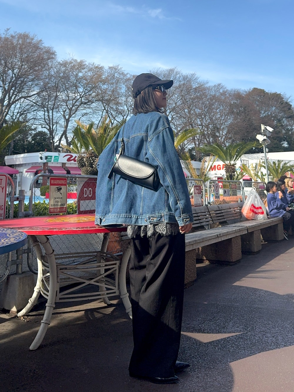 ブラック系のスラックス、ブルー系のデニムジャケット、ブラック系のボディバッグ/ウエストポーチを着用したレディースの春コーディネートの2枚目の写真