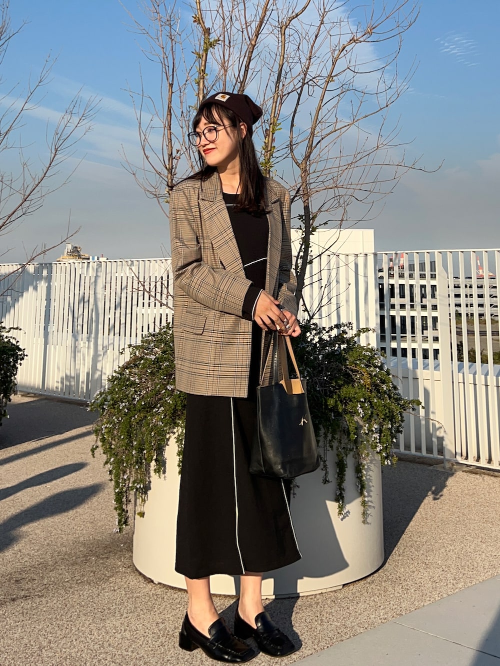 ブラック系のワンピース、ブラック系のハンドバッグ、ブラック系のローファーを着用したレディースの秋コーディネートの2枚目の写真