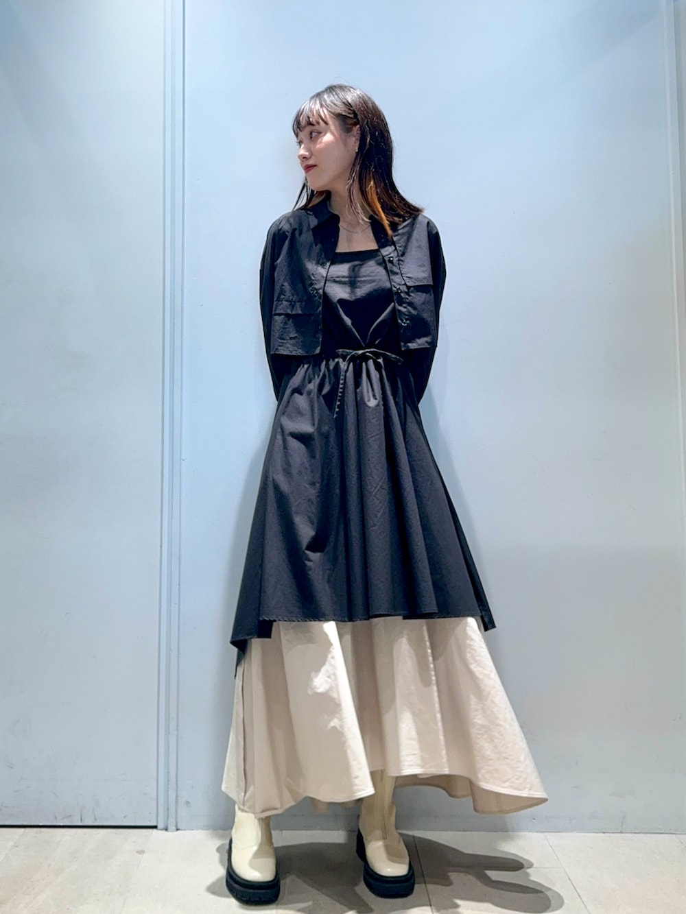 ブラック系のシャツワンピース、ベージュ系のスカート、ベージュ系のブーツを着用したレディースの秋コーディネートの3枚目の写真