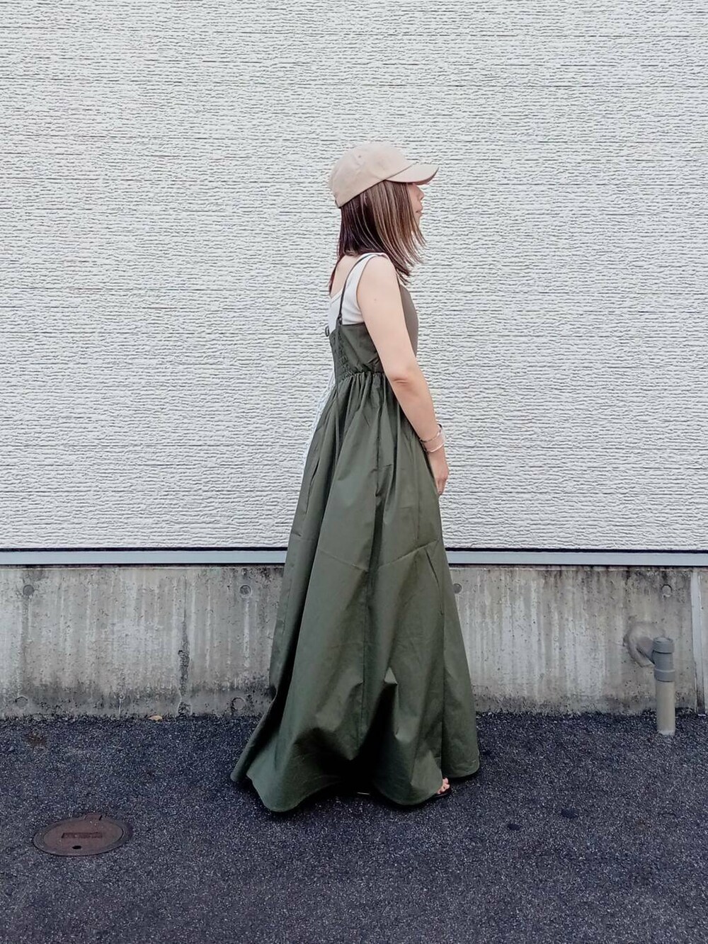 グリーン系のワンピース、ホワイト系のハンドバッグ、ベージュ系のキャップを着用したレディースの夏コーディネートの3枚目の写真