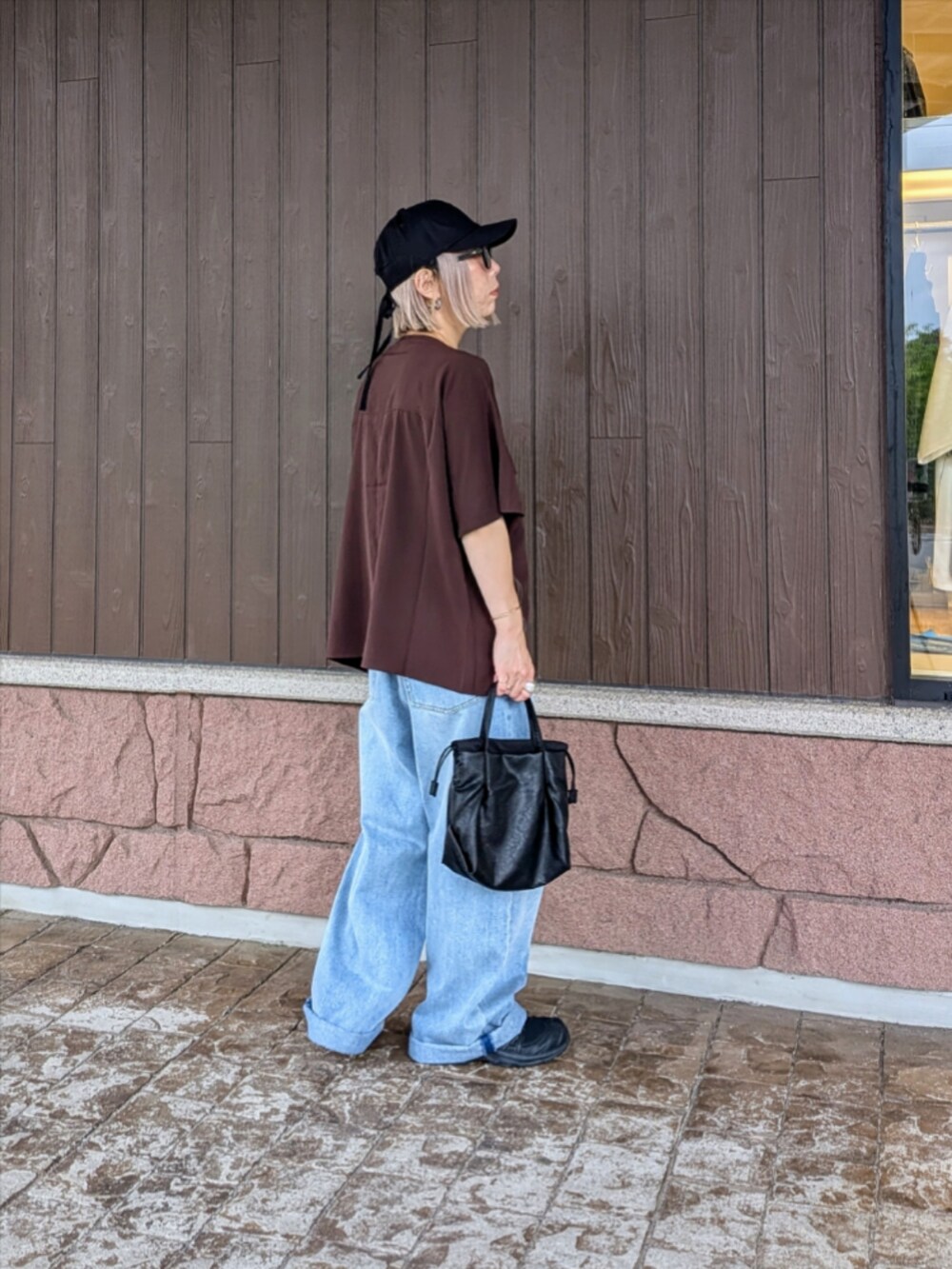 ブラウン系のシャツ/ブラウス、ブルー系のデニムパンツ、ブラック系のスニーカーを着用したレディースの夏コーディネートの3枚目の写真