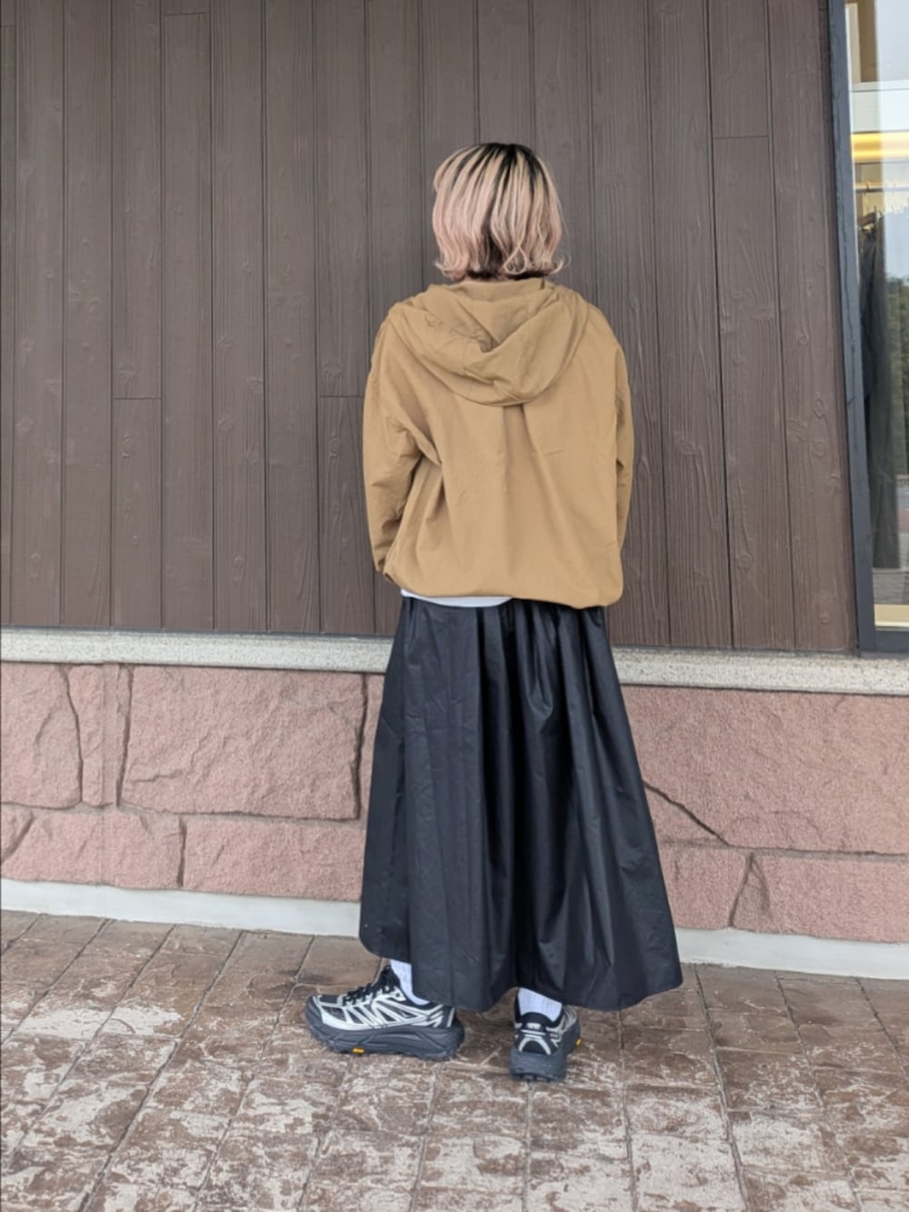 イエロー系のブルゾン、ブラック系のスカート、ブラック系のスニーカーを着用したレディースの春コーディネートの3枚目の写真