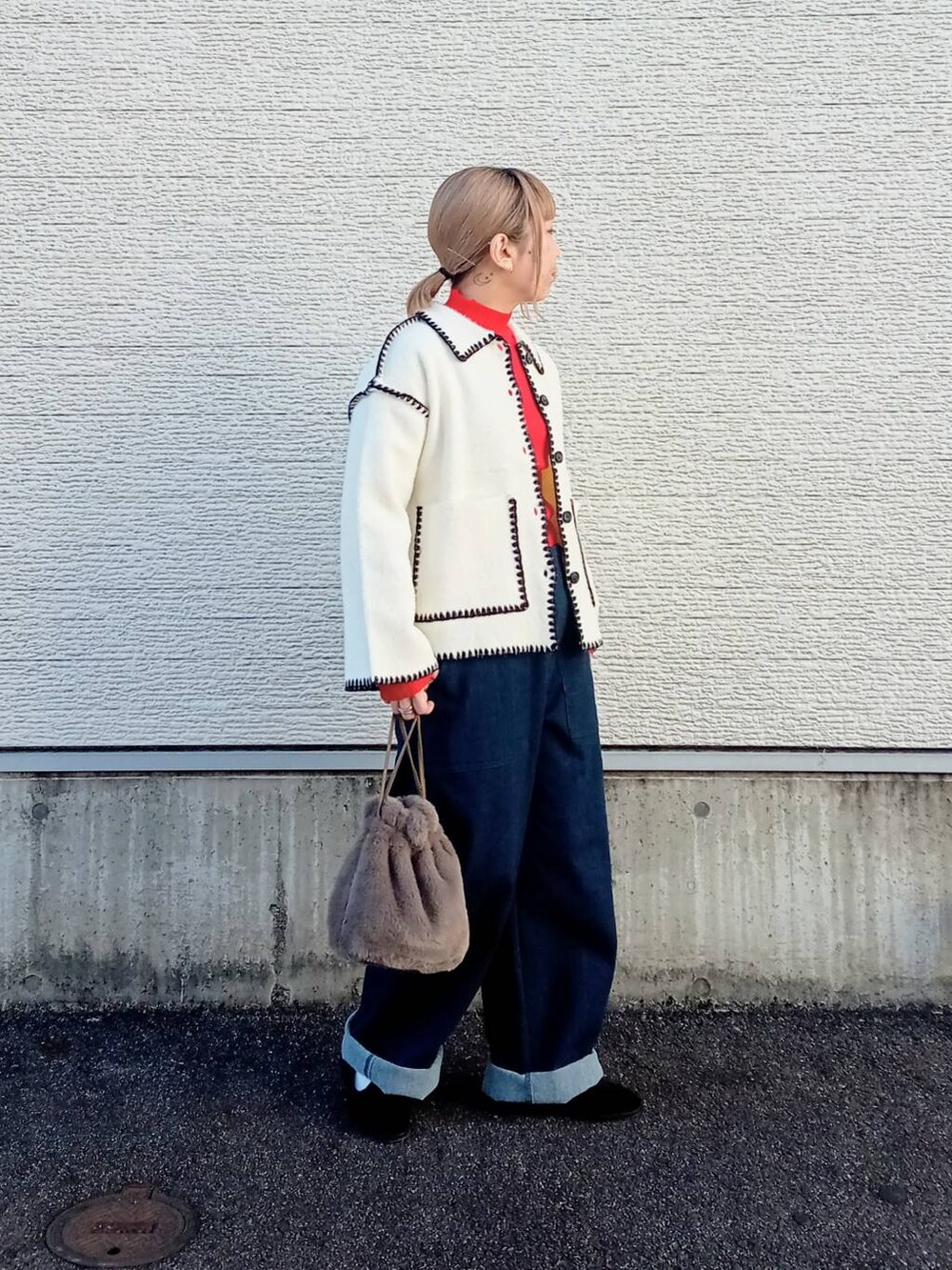 レッド系のニット/セーター、ブルー系のデニムパンツ、ホワイト系のその他アウターを着用したレディースの冬コーディネートの5枚目の写真