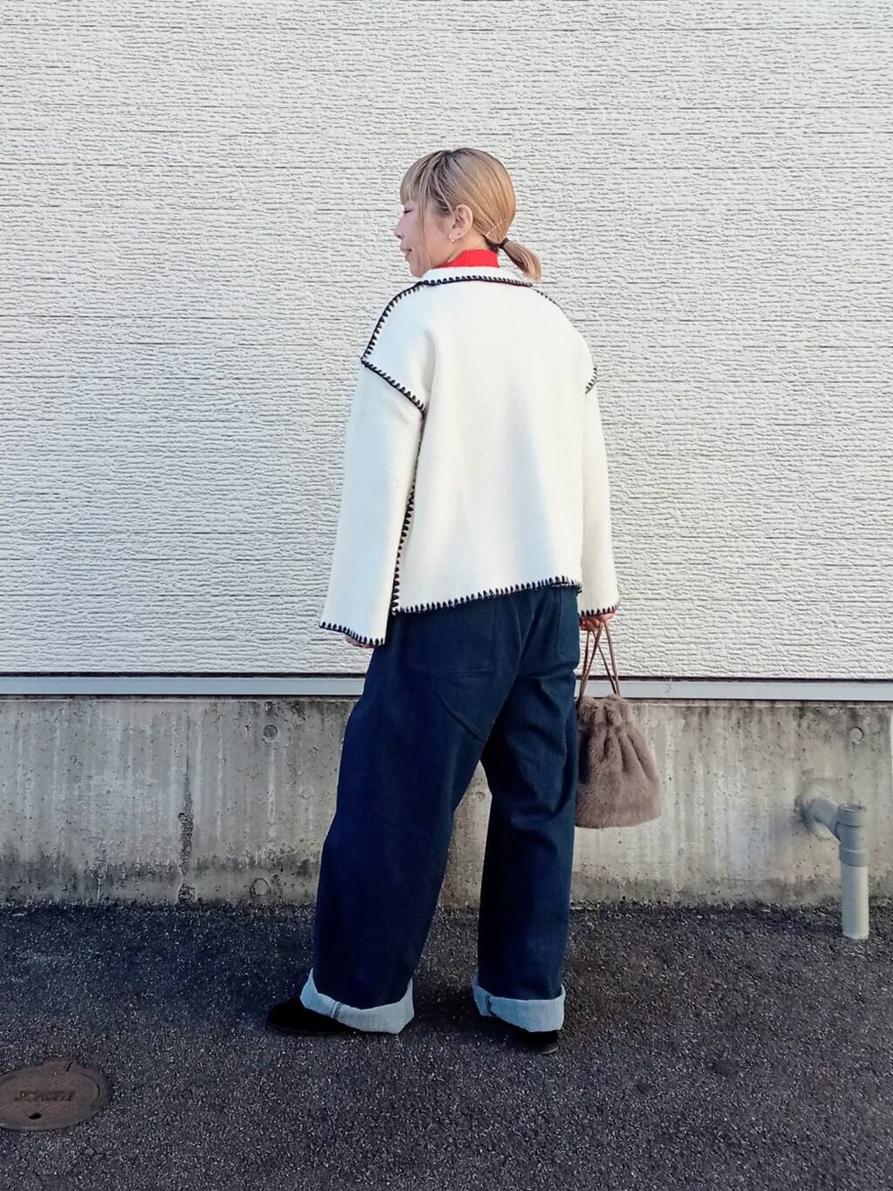 レッド系のニット/セーター、ブルー系のデニムパンツ、ホワイト系のその他アウターを着用したレディースの冬コーディネートの2枚目の写真