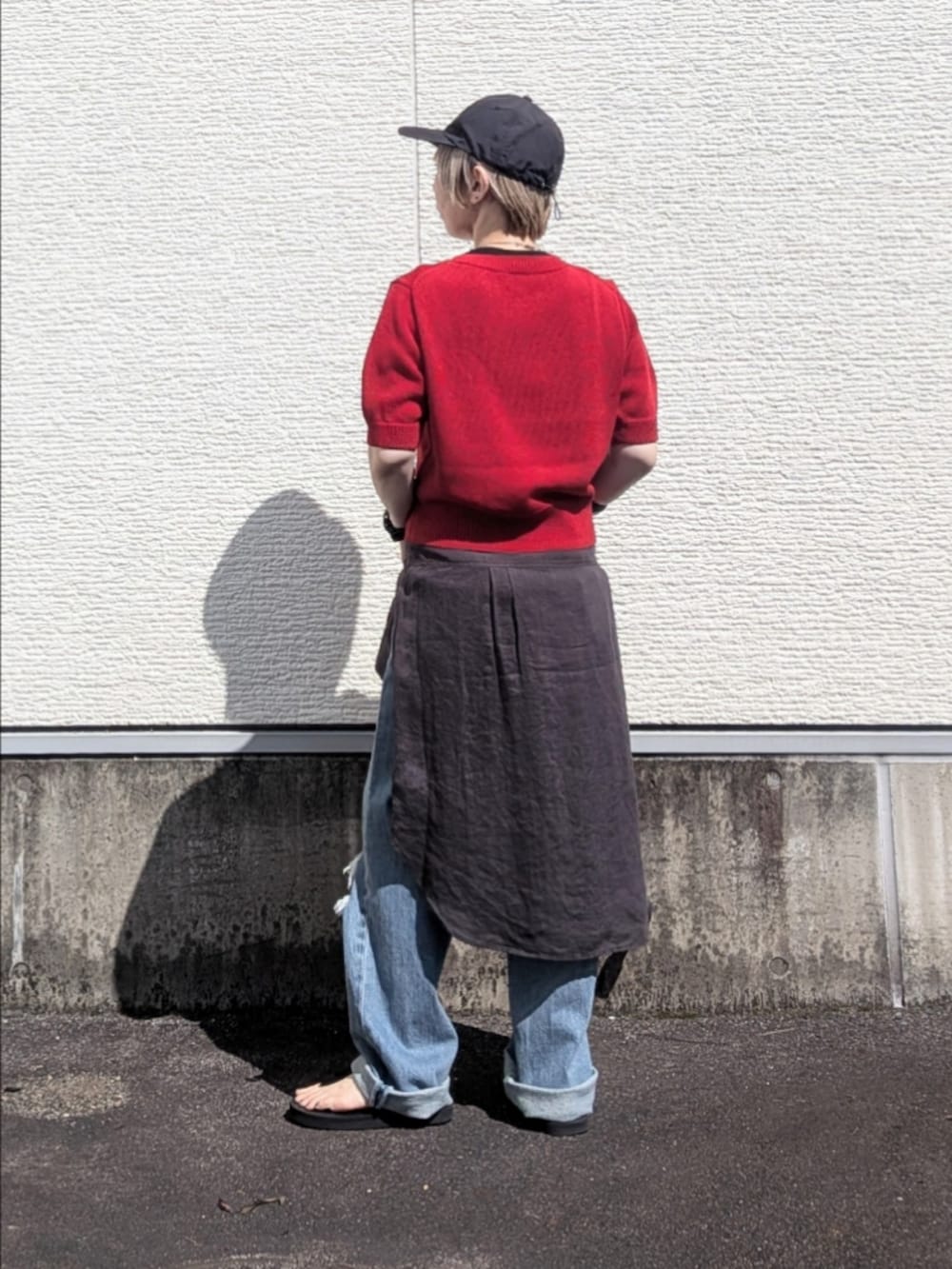 レッド系のニット/セーター、ブルー系のデニムパンツ、グレー系のシャツ/ブラウスを着用したレディースの夏コーディネートの3枚目の写真
