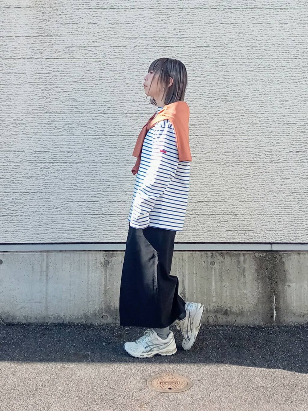 ブラック系のスカート、ブルー系のTシャツ/カットソー、オレンジ系のカーディガン/ボレロを着用したレディースの春コーディネートの2枚目の写真