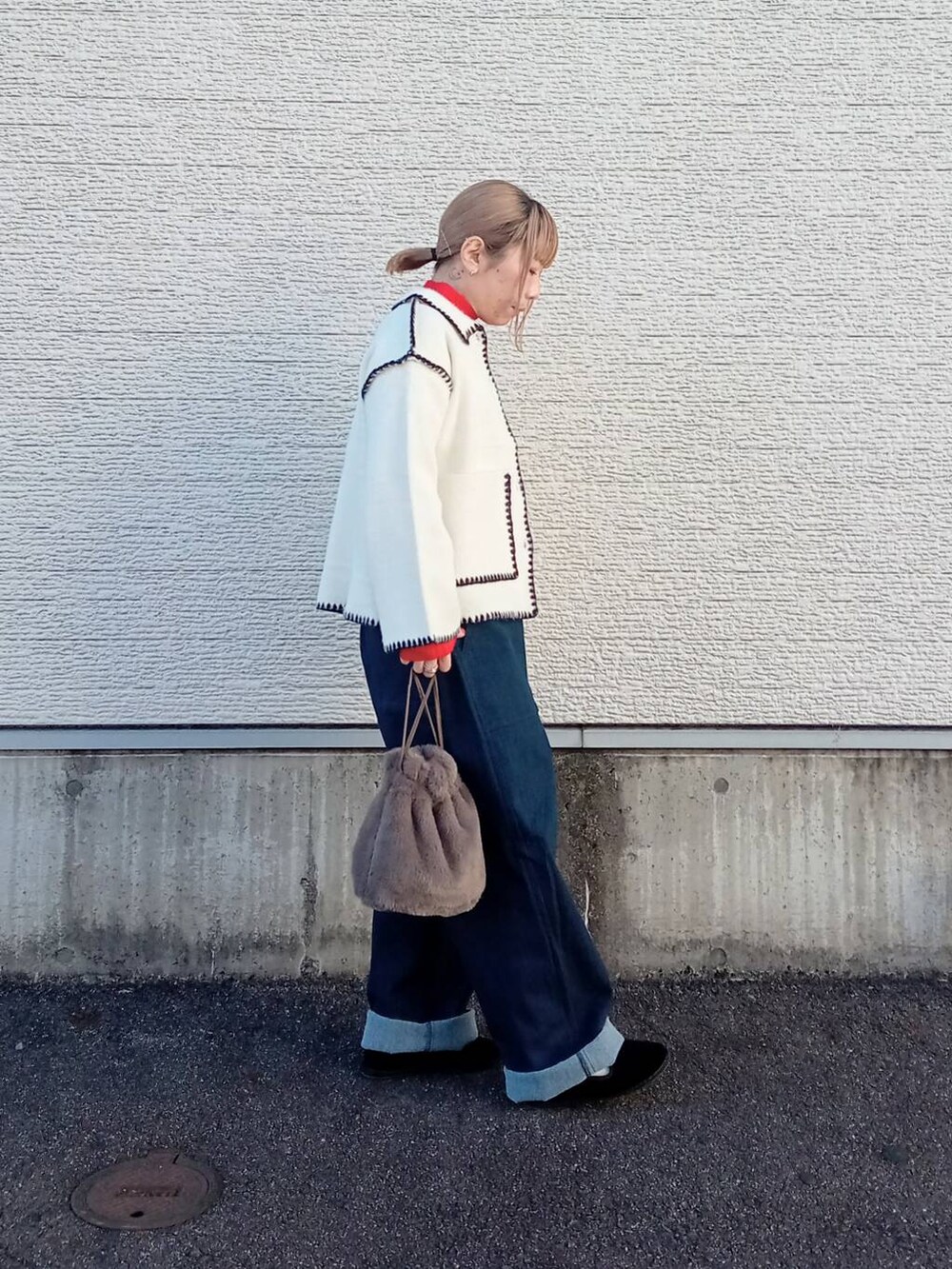 レッド系のニット/セーター、ブルー系のデニムパンツ、ホワイト系のその他アウターを着用したレディースの冬コーディネートの4枚目の写真