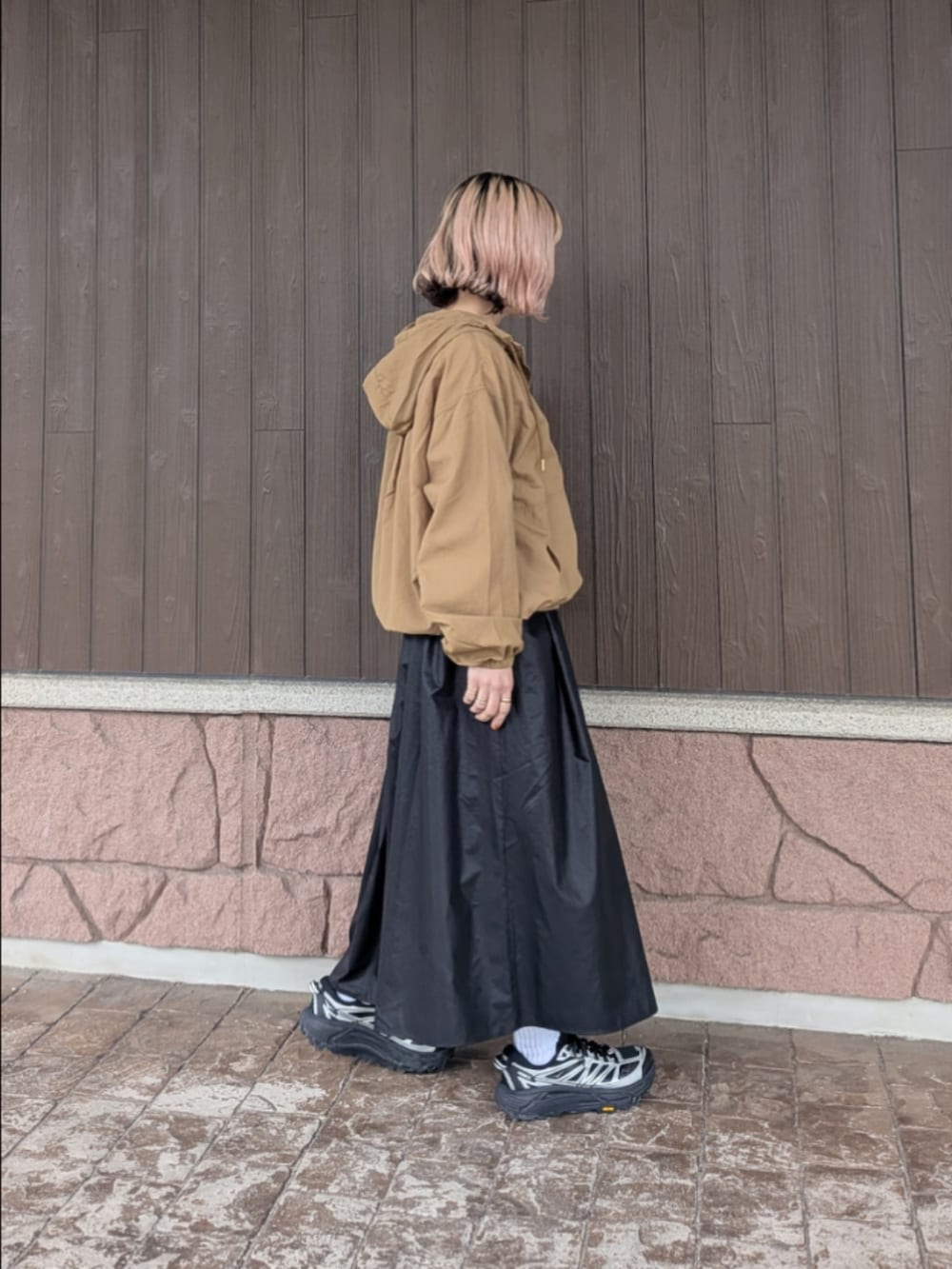 イエロー系のブルゾン、ブラック系のスカート、ブラック系のスニーカーを着用したレディースの春コーディネートの2枚目の写真