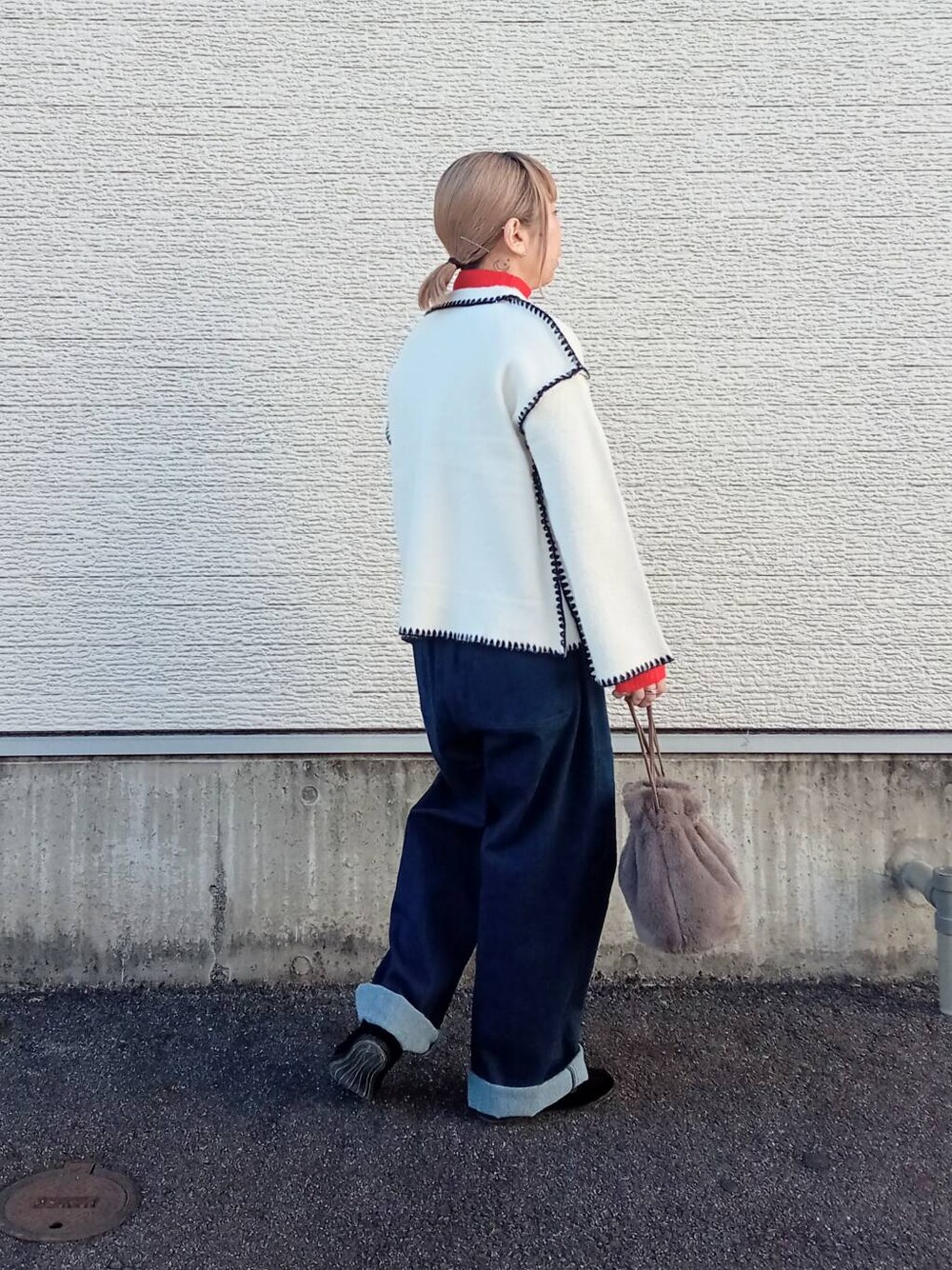 レッド系のニット/セーター、ブルー系のデニムパンツ、ホワイト系のその他アウターを着用したレディースの冬コーディネートの3枚目の写真