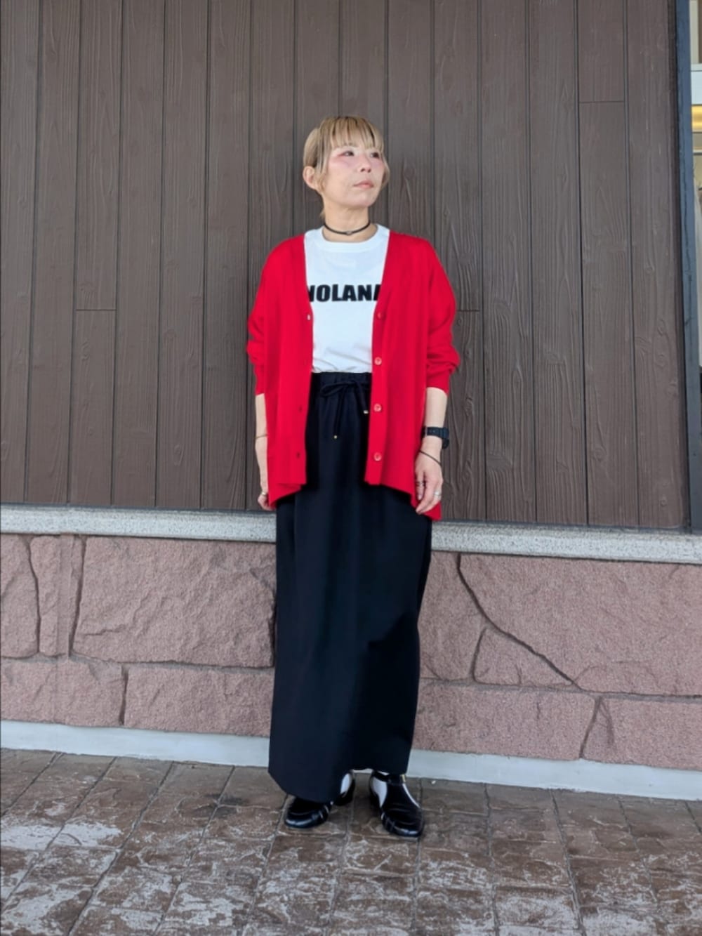 ブラック系のスカート、ホワイト系のTシャツ/カットソー、レッド系のニット/セーターを着用したレディースの春コーディネートの2枚目の写真