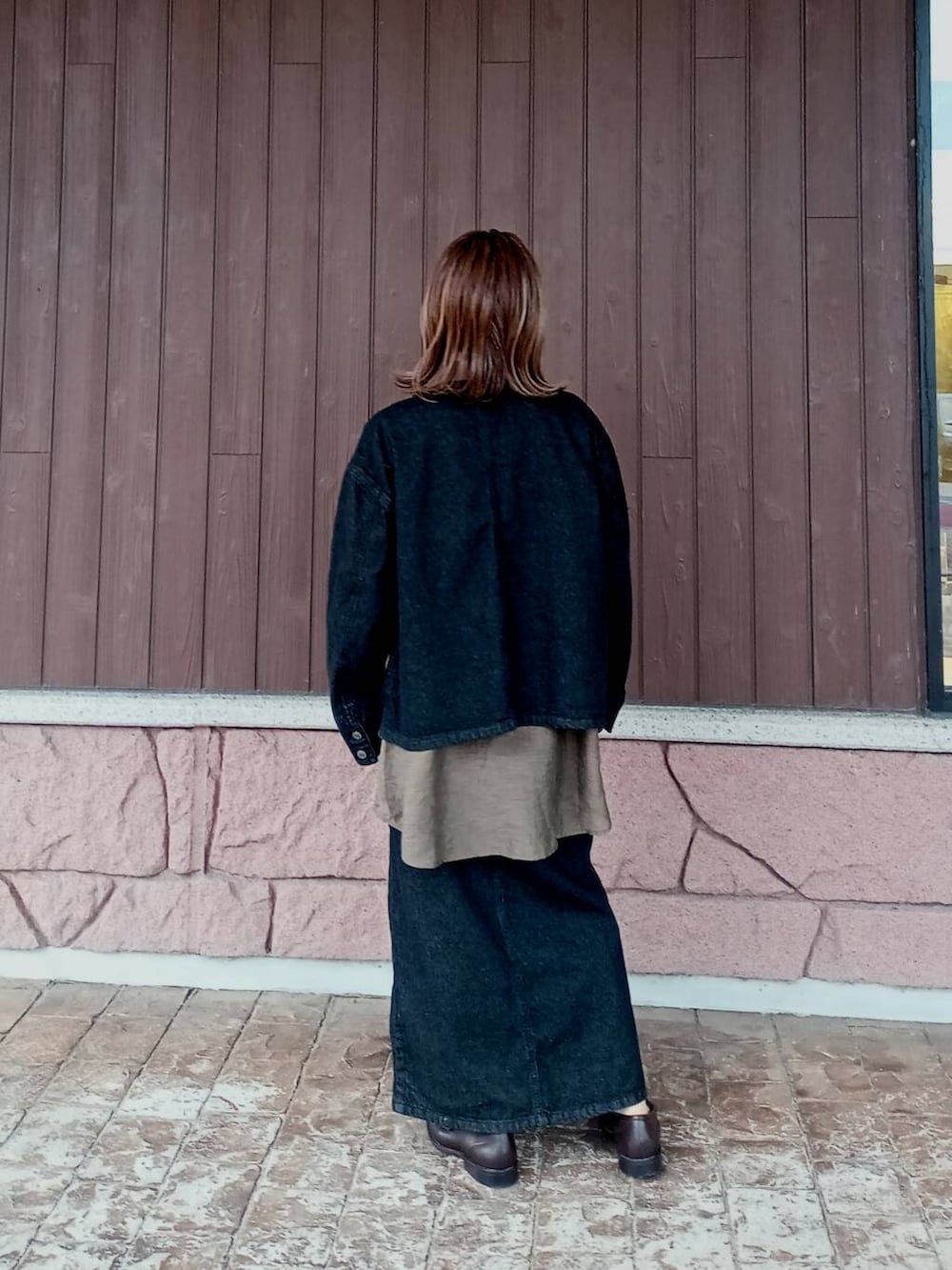 ブラウン系のローファー、ブラック系のスカート、ブラック系のデニムジャケットを着用したレディースの秋コーディネートの6枚目の写真