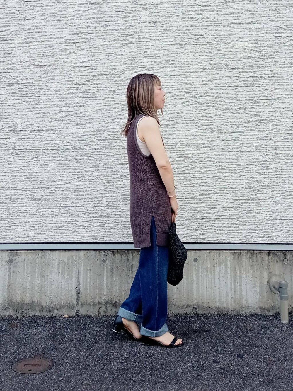 ブラック系のトートバッグ、ブルー系のデニムパンツ、ブラック系のニット/セーターを着用したレディースの夏コーディネートの2枚目の写真