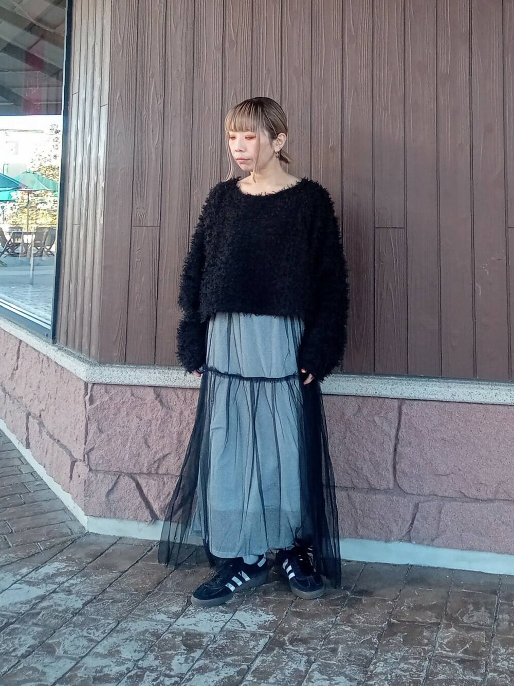 シルバー系のスカート、ブラック系のニット/セーターを着用したレディースの冬コーディネートの2枚目の写真