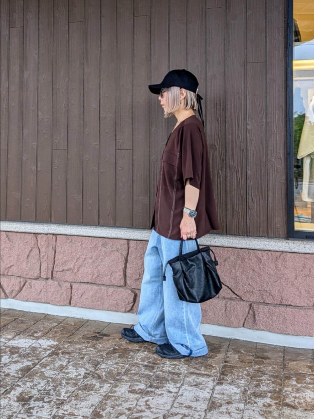 ブラウン系のシャツ/ブラウス、ブルー系のデニムパンツ、ブラック系のスニーカーを着用したレディースの夏コーディネートの2枚目の写真