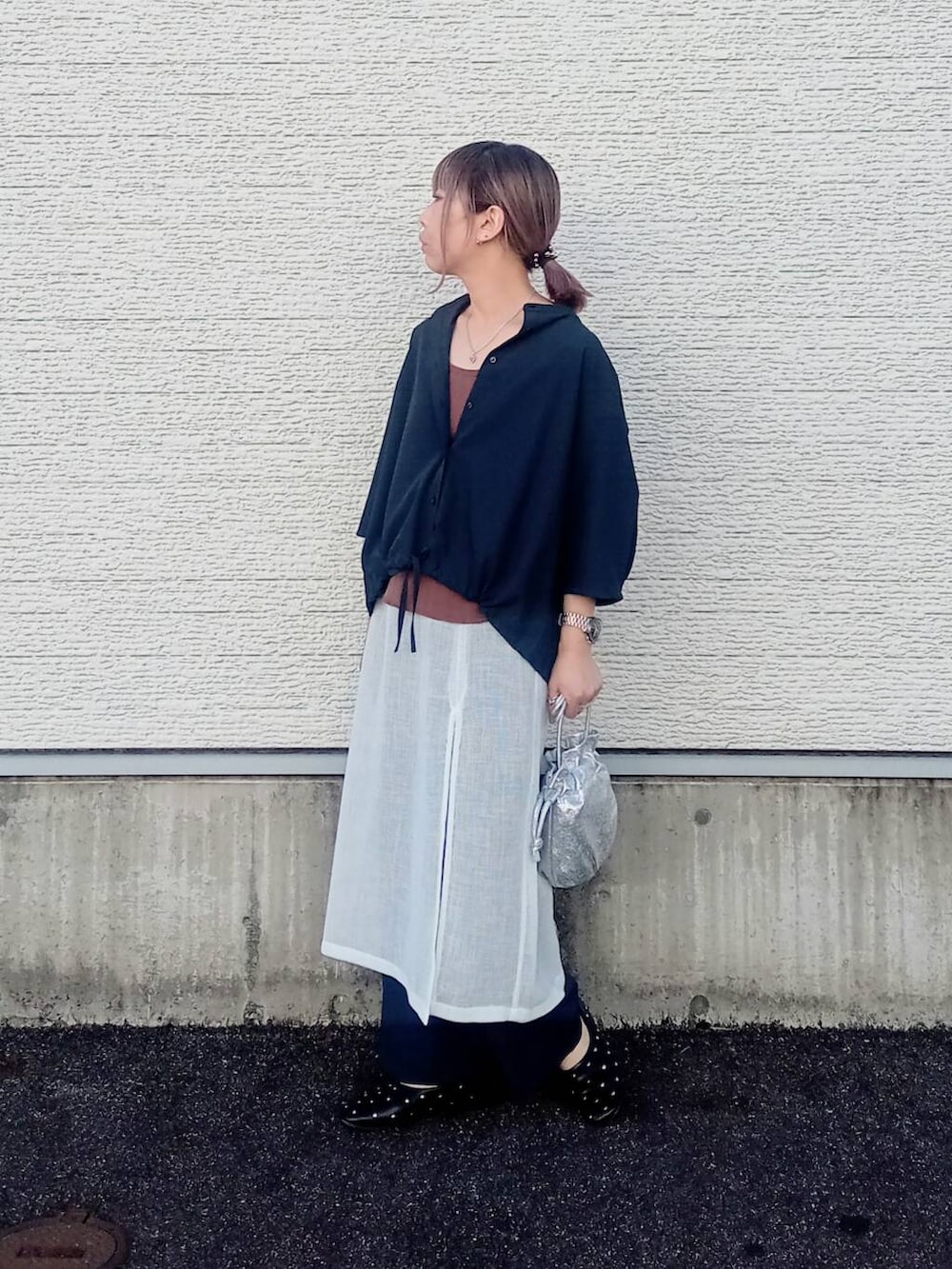 ホワイト系のスカート、ブラック系のパンプス、シルバー系のショルダーバッグを着用したレディースの春コーディネートの3枚目の写真